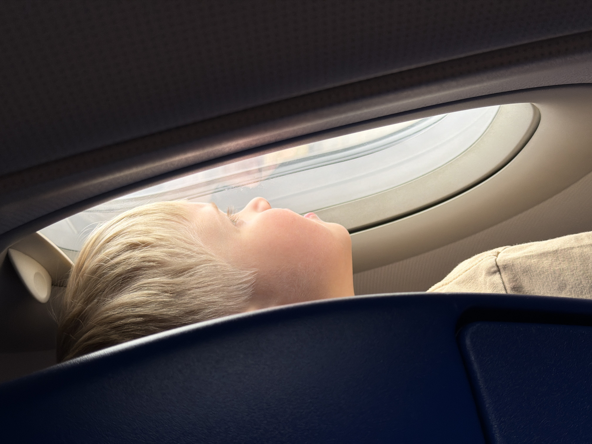 Child rests against airplane seat near window in Russia