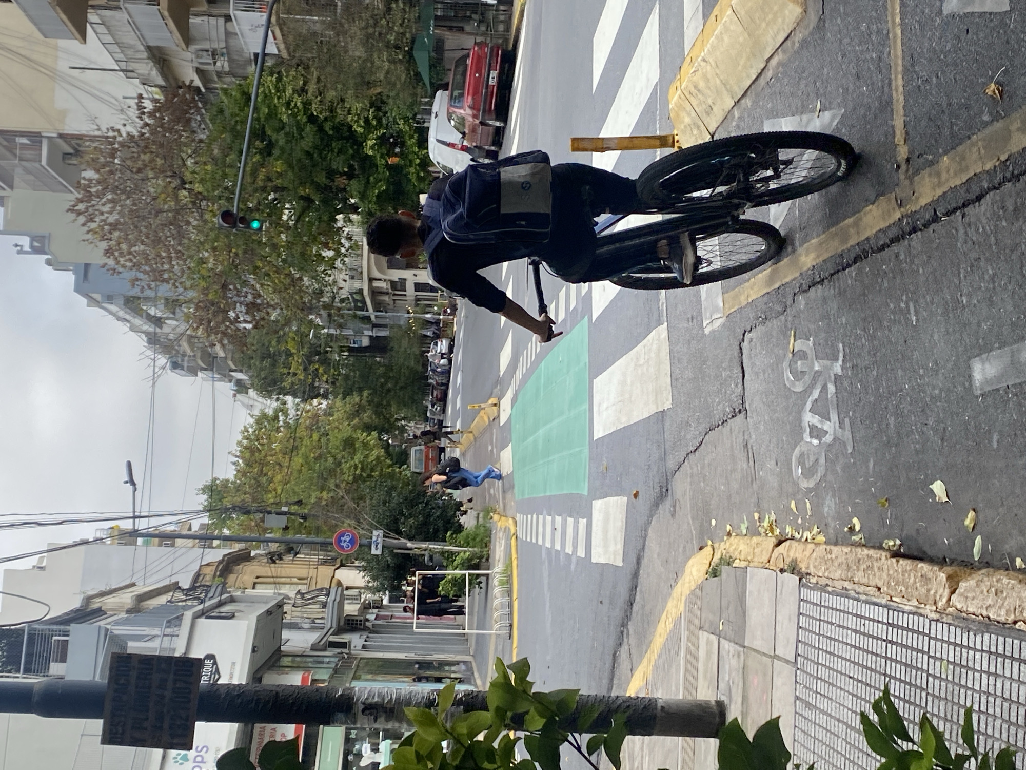 Cyclist rides through Buenos Aires street under overcast skies