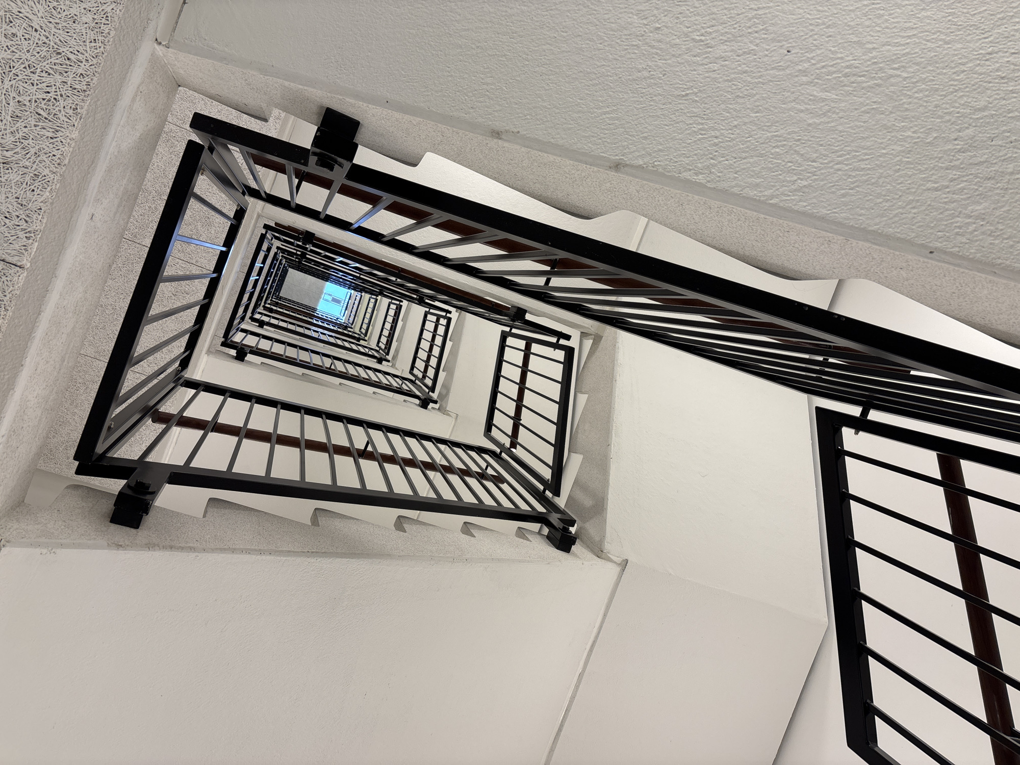 Copenhagen stairwell photographed from below shows white walls, black railings
