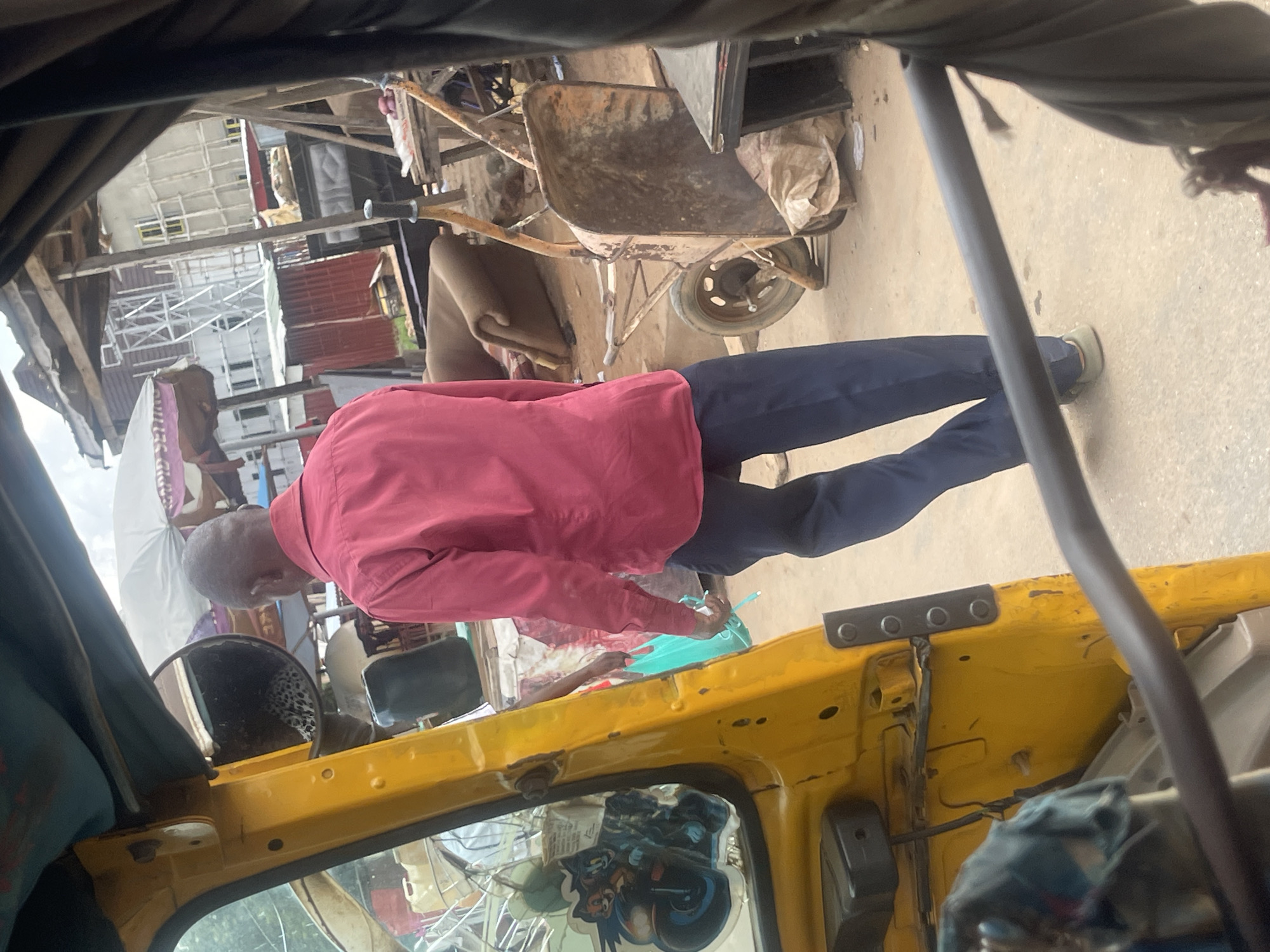 Street life around a yellow auto-rickshaw in Abuja construction zone