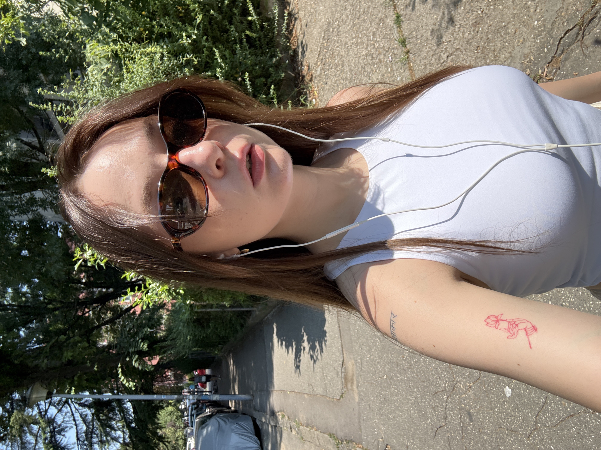 Sunny selfie moment in Belgrade, white earbuds and lotus tattoo