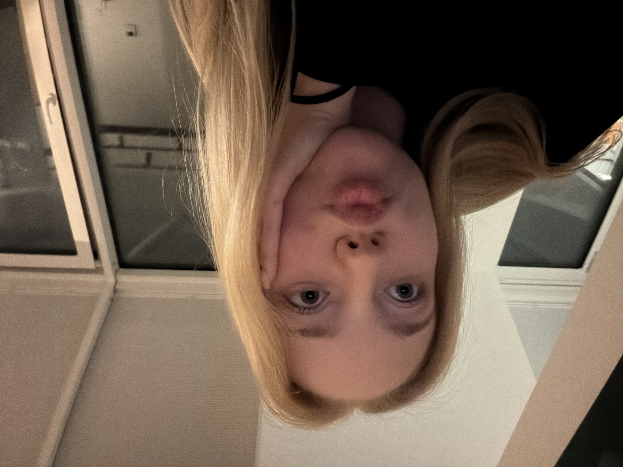 Blonde person photographed making expressions on white surface