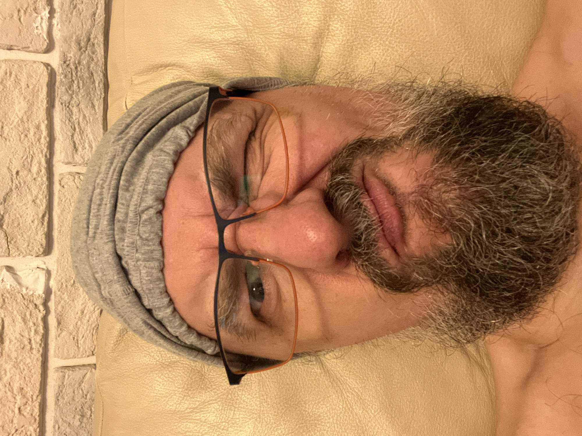 Winking at the camera, beanie and orange-rimmed glasses on.