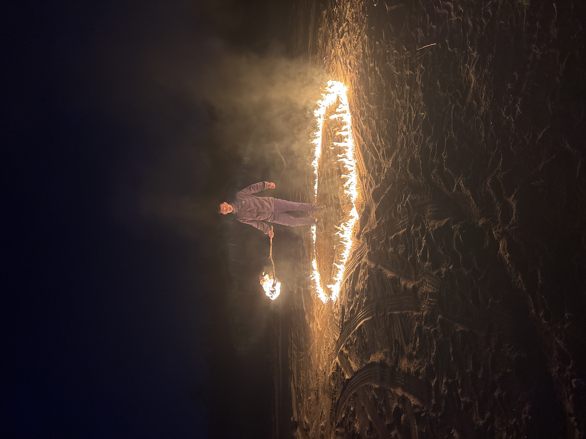 Man conducts nighttime fire ceremony on Russian beach