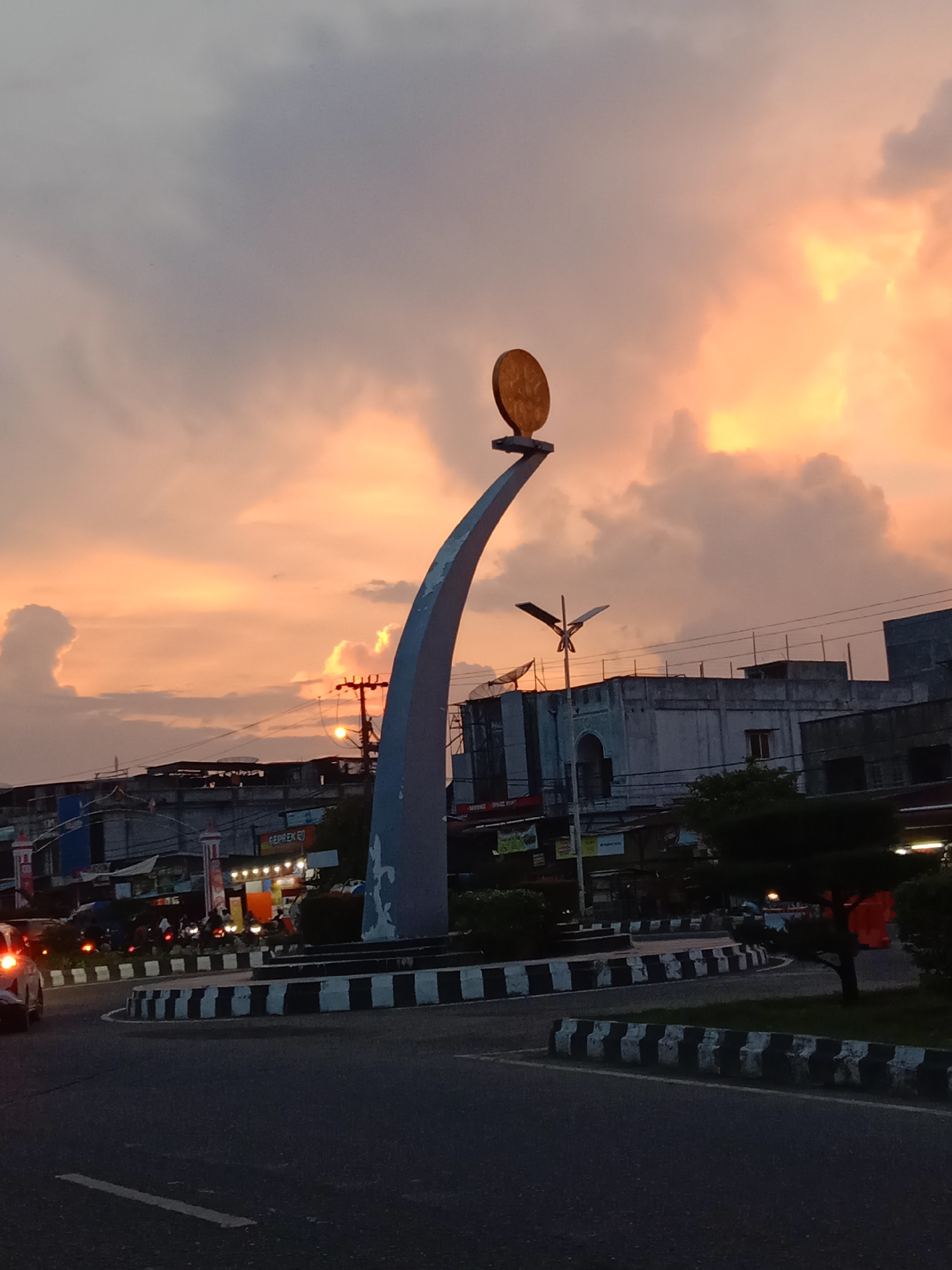 Dramatic sunset illuminates Lhokseumawe roundabout with golden hour colors