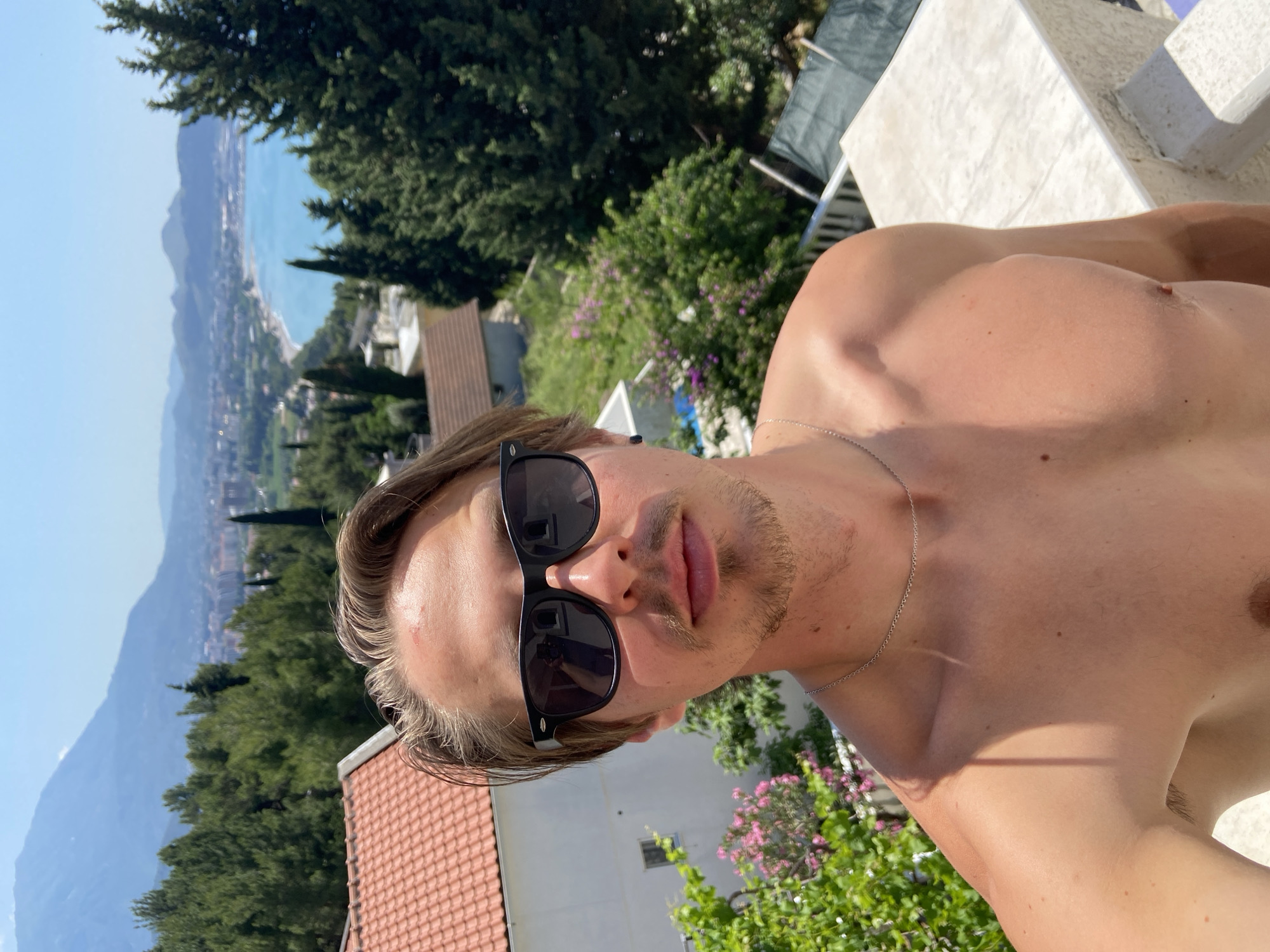 Man poses shirtless with sunglasses on Montenegro balcony