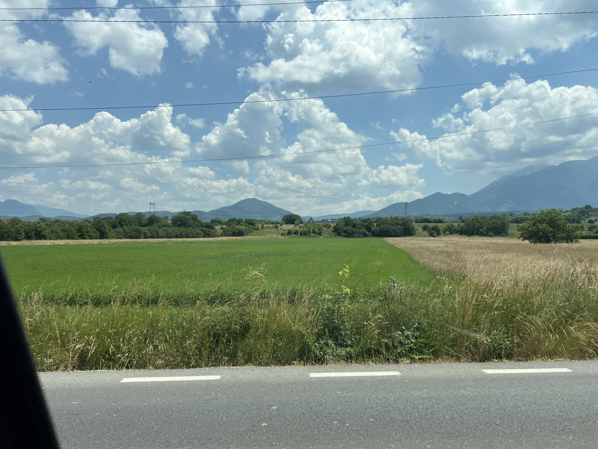 Rural highway drive past grasslands, mountains, and a warehouse stop
