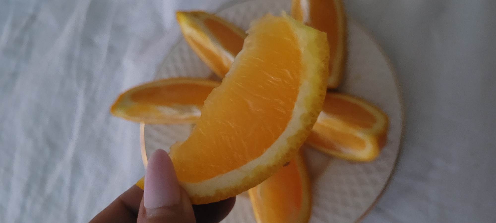 Hand holding a bright orange slice, shot from above in Riga.