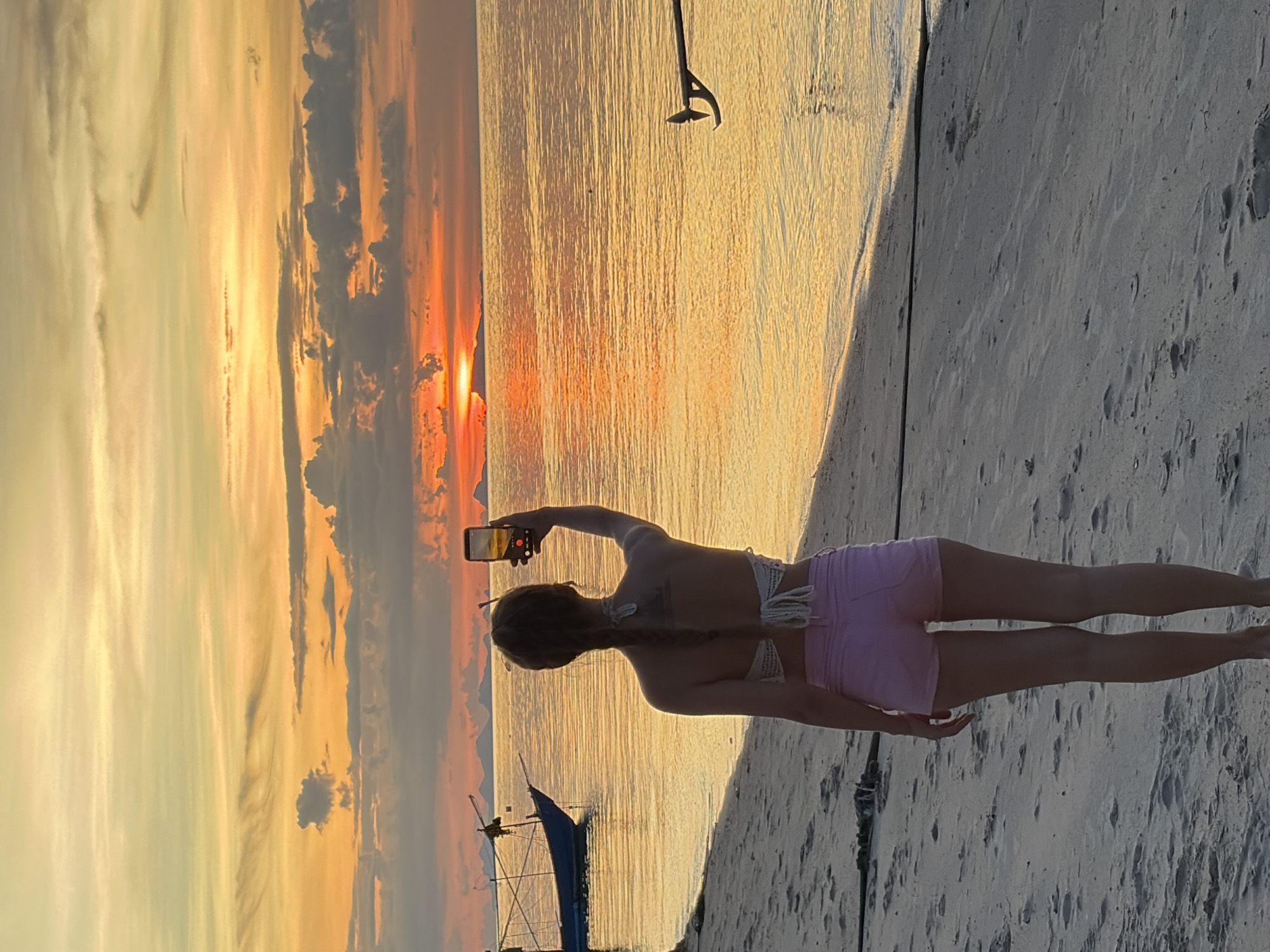 Golden hour on a Thai beach with boats and selfies