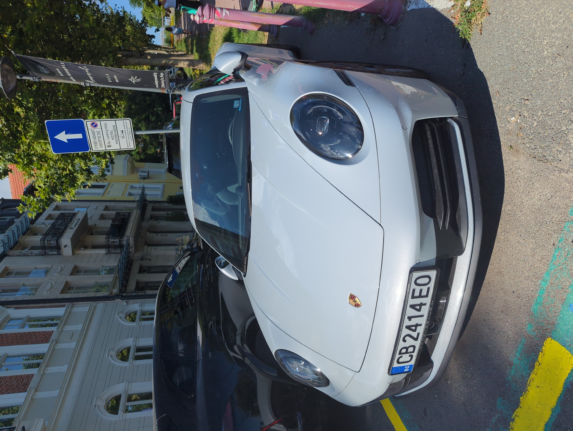 Porsche and Rolls-Royce parked near a shaded walkway in Bulgaria