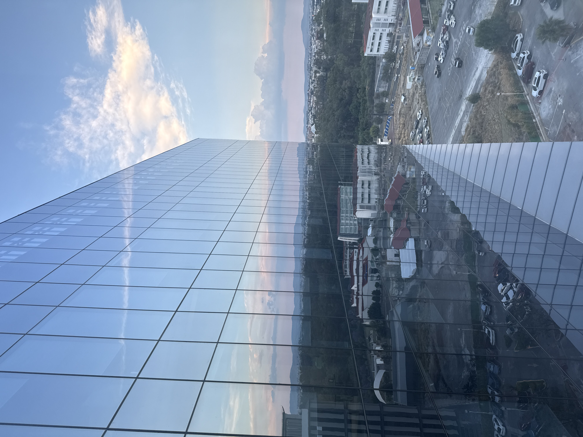 Modern glass building photographed reflecting urban skyline at night