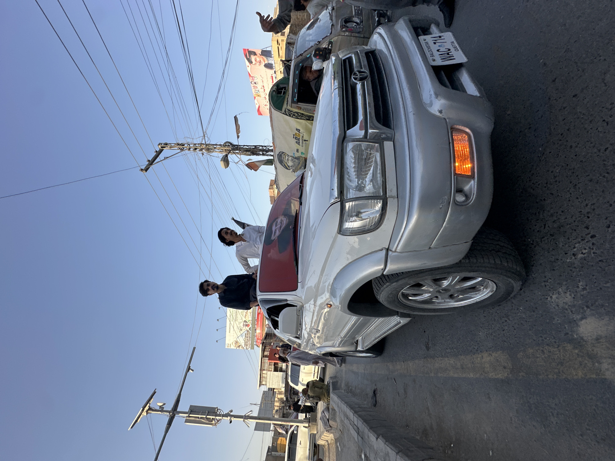 Flag-draped vehicle procession winds through Quetta at sunset