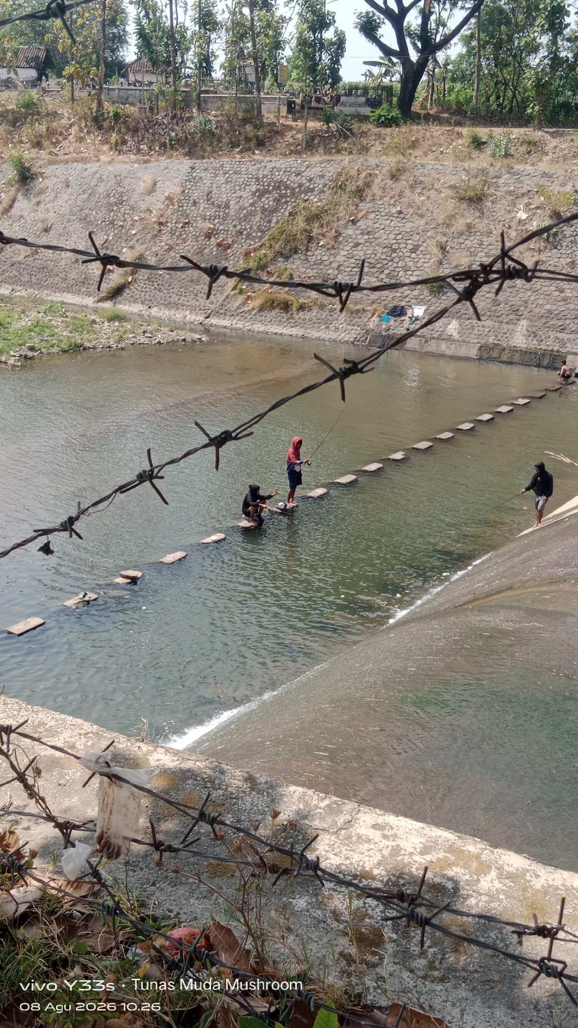 Kids and locals hang out at a concrete dam in Tanjung