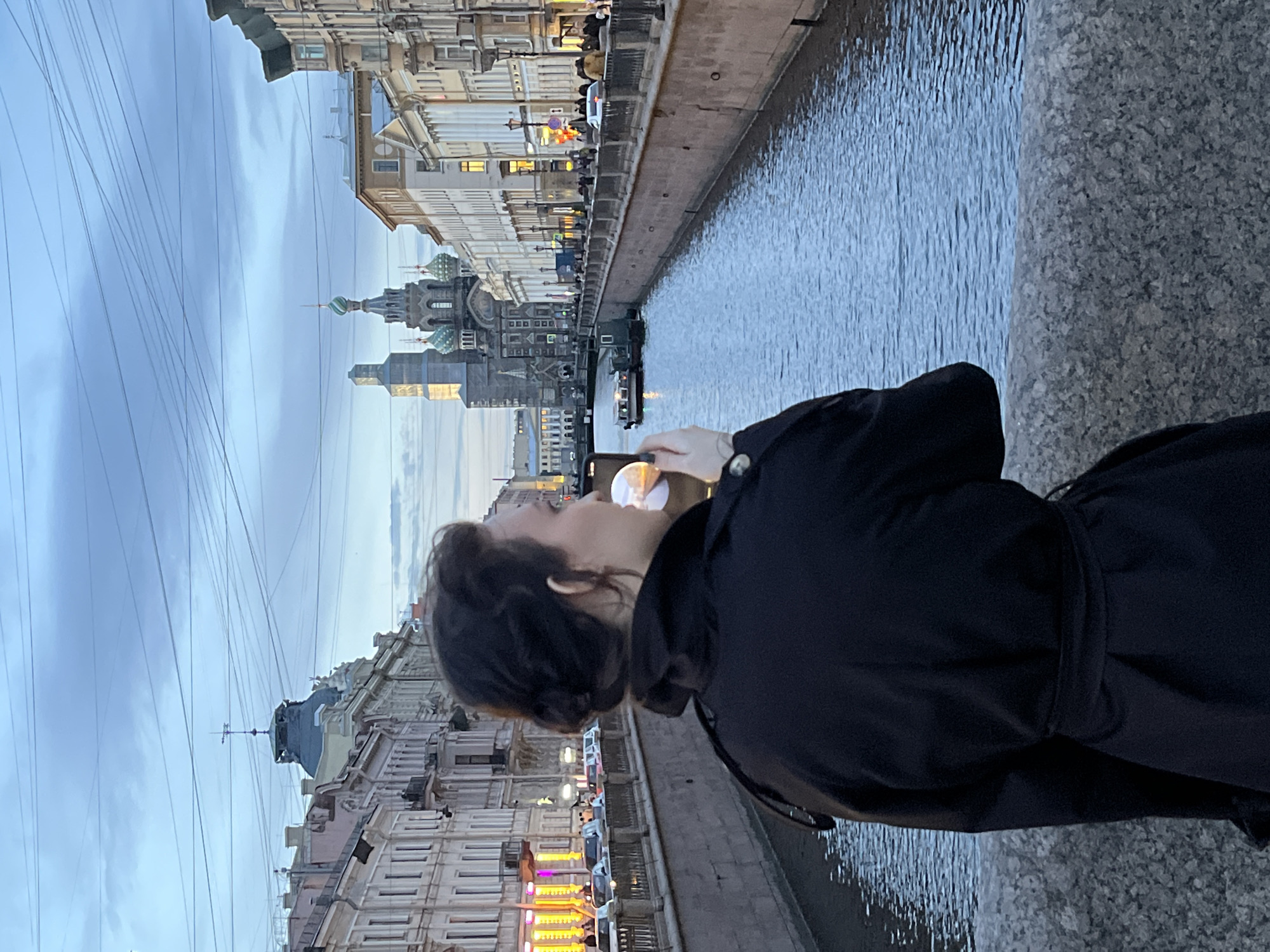 Woman photographs Saint Petersburg canal from granite bridge