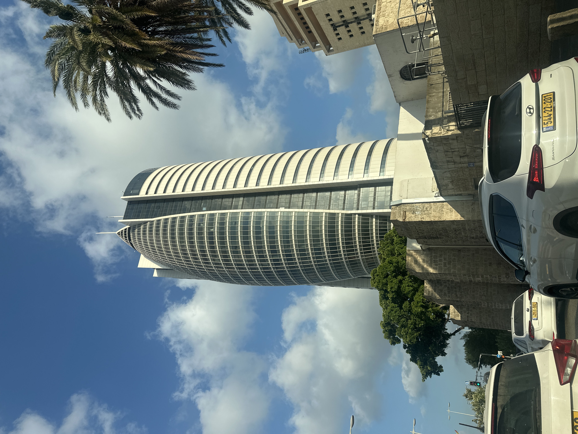 Haifa streets: glass tower, palm-lined boulevard, rainbow flag