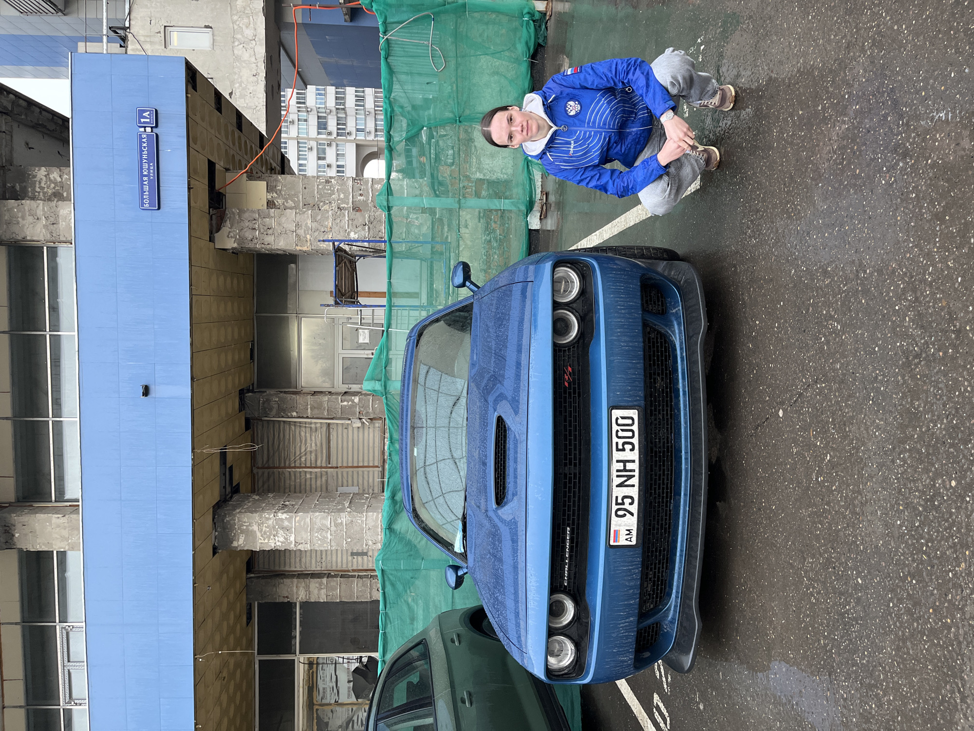 Woman poses with blue Dodge Challenger in Moscow
