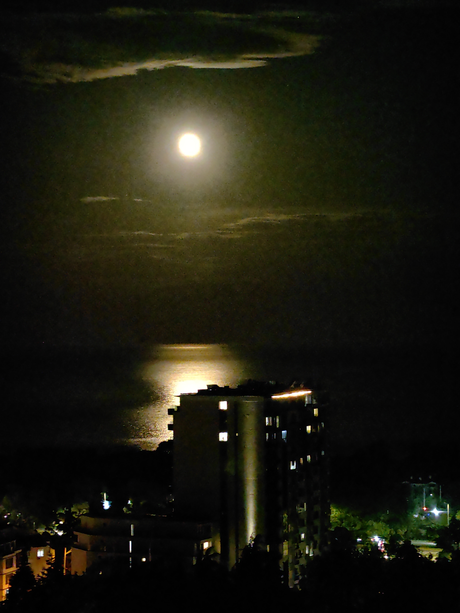 Full moon illuminates unknown city during evening hours