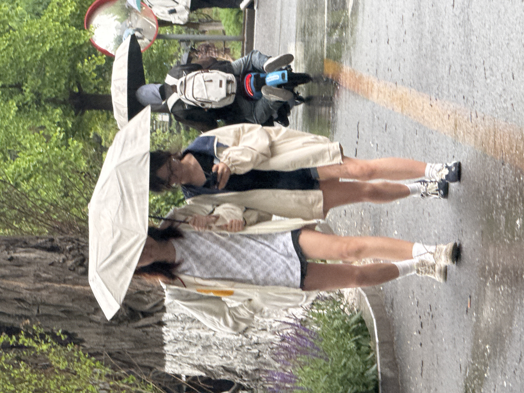 Two pedestrians share umbrella on rainy Zhongtun street
