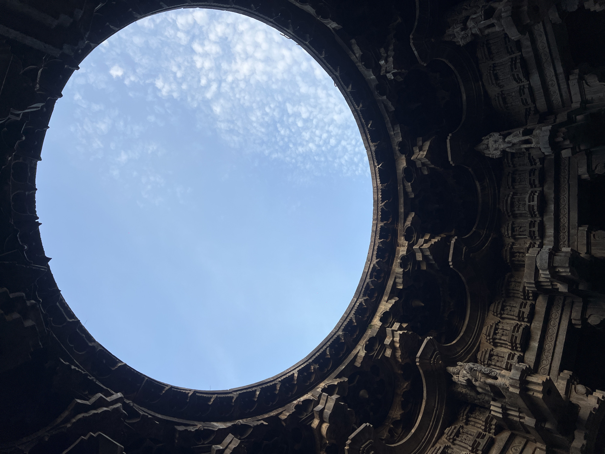 Inside a circular stone temple, looking up through the oculus