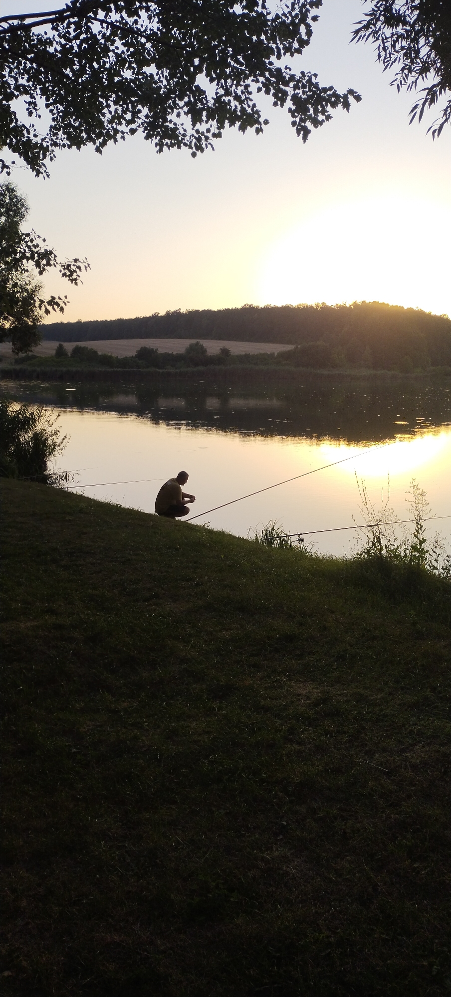 Fishing at dusk on a calm Ukrainian riverbank at sunset