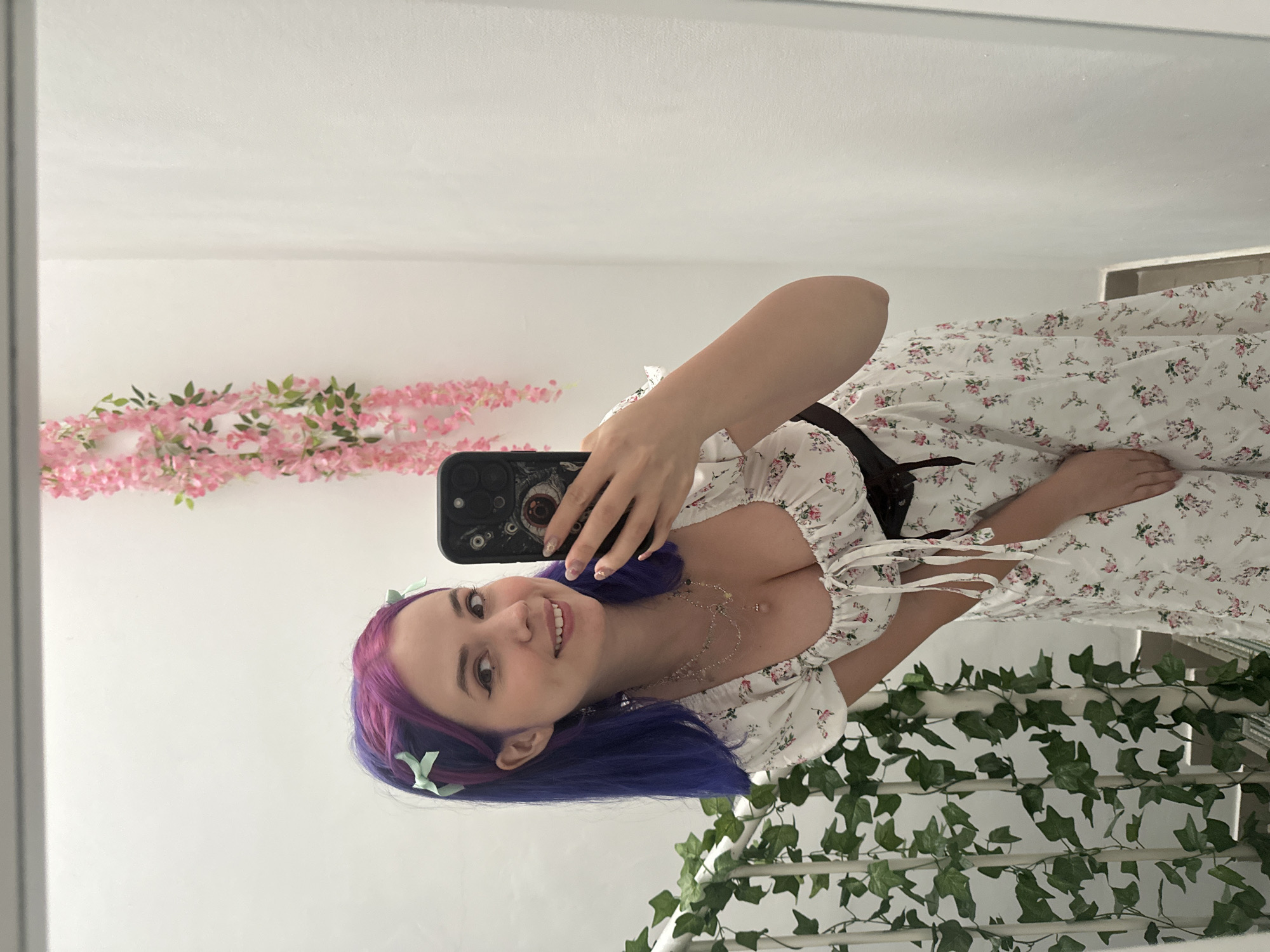 Woman takes mirror selfies in colorful hair and floral dress