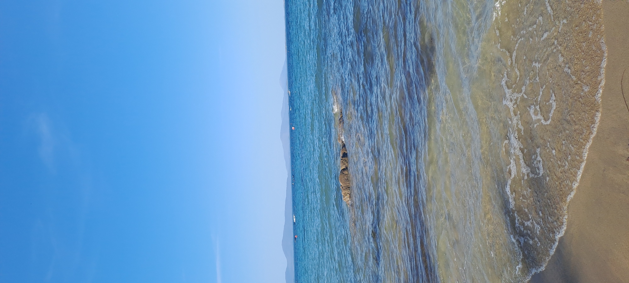 Sunny afternoon on a calm Irish beach with seaweed and stone walls