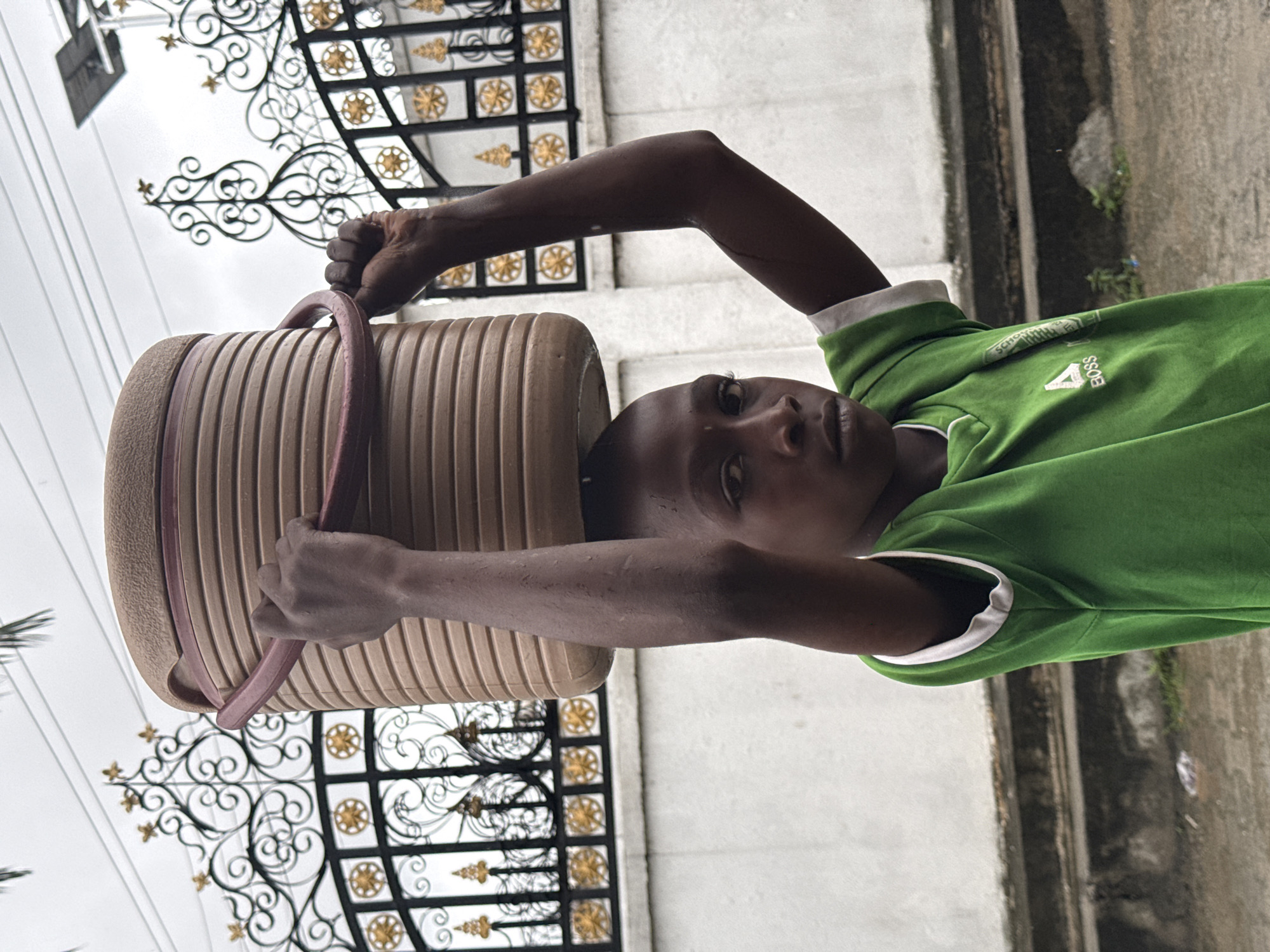 Children walk wet streets in Ado during overcast afternoon