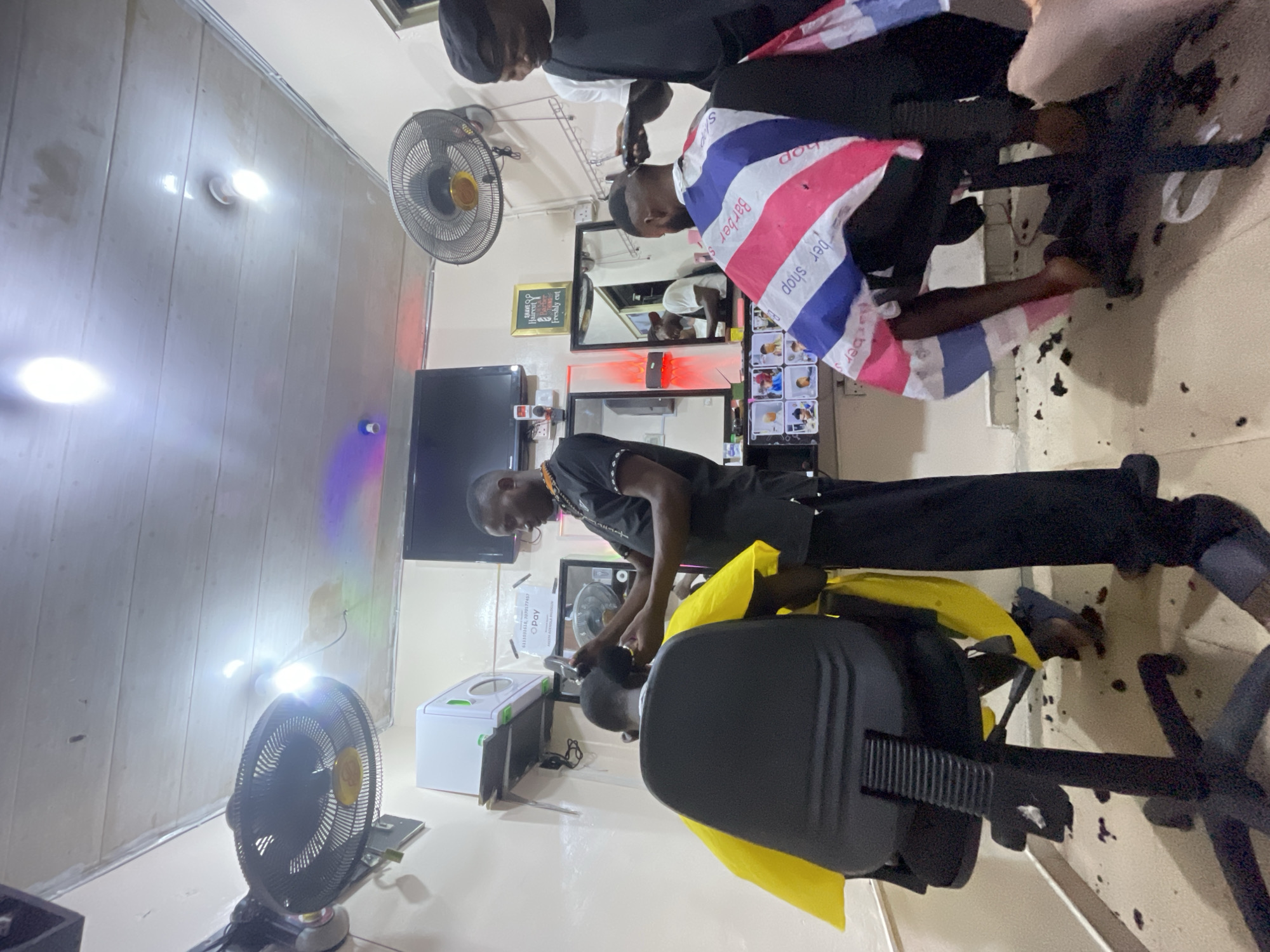 Busy barbershop serves customers in Ado, Nigeria alleyway