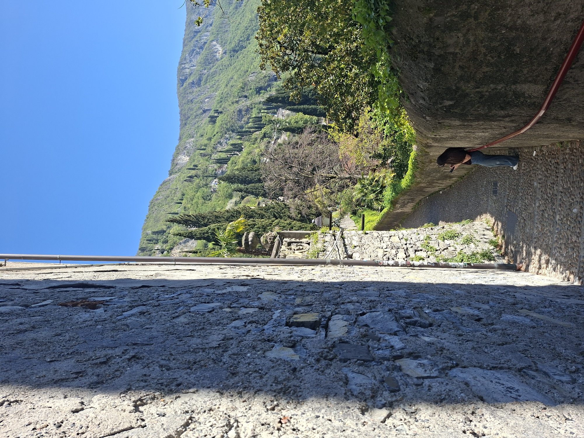 Person walks cobblestone path in Varenna, Italy
