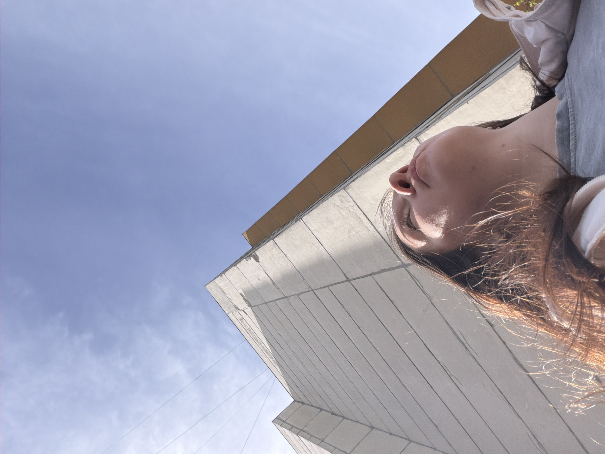 Woman gazes upward at building under clear skies in Staraya