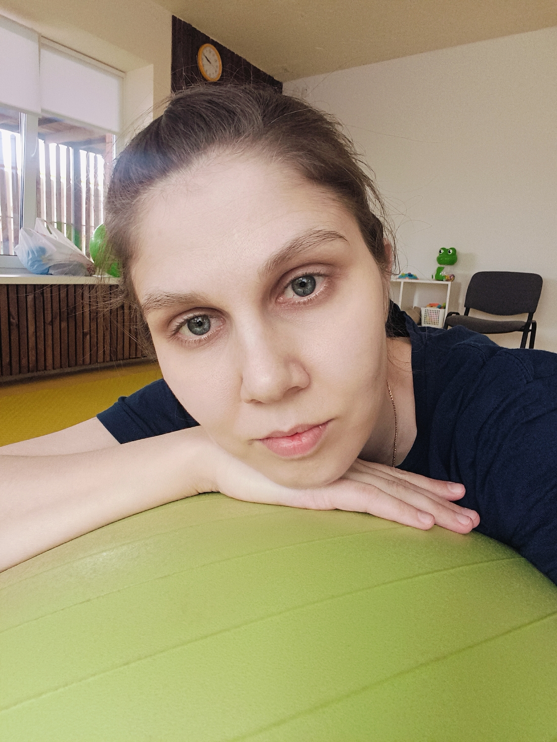 Woman rests on lime-green exercise ball in casual moment