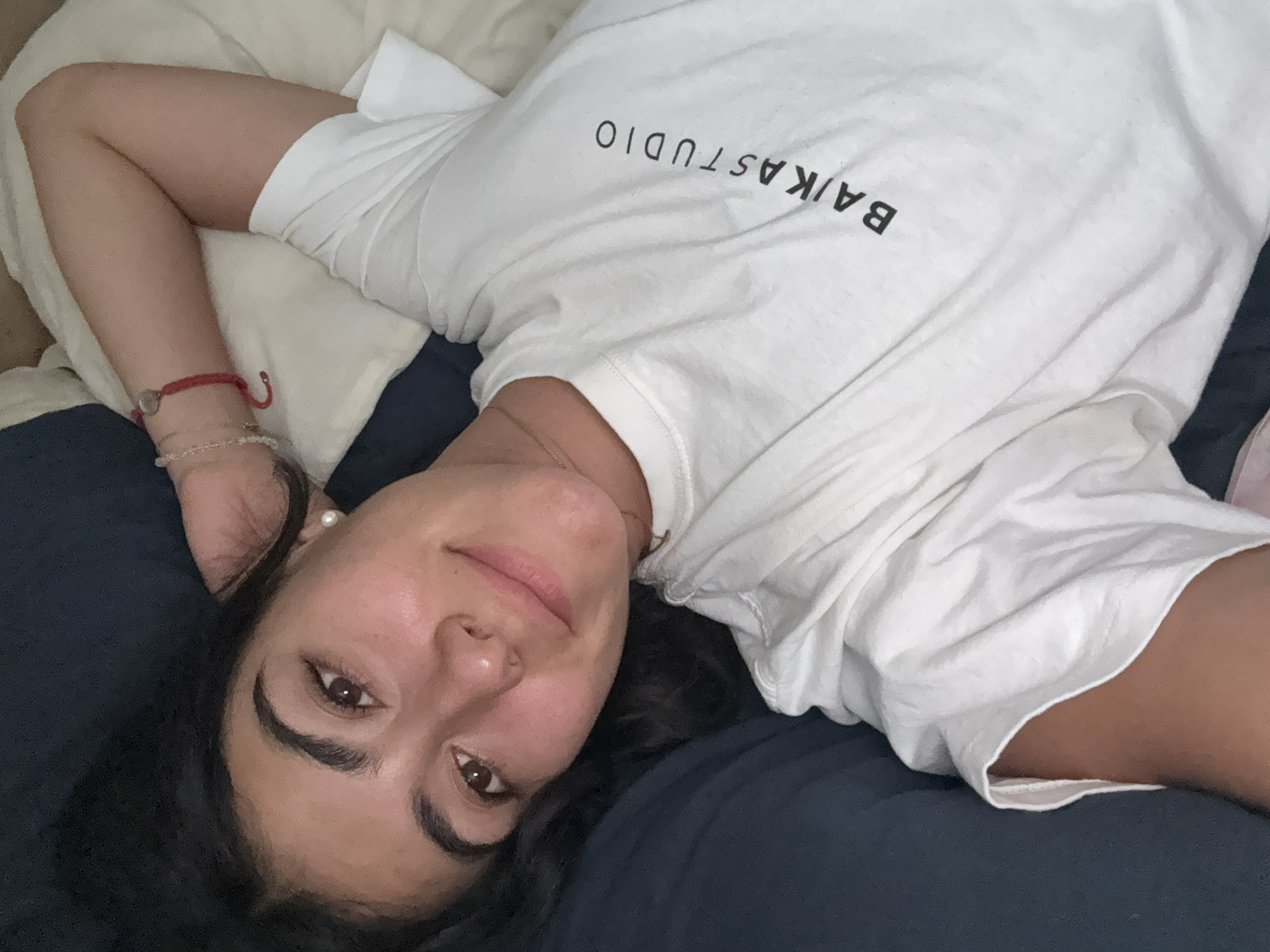 Woman rests on bed in Puebla wearing branded shirt