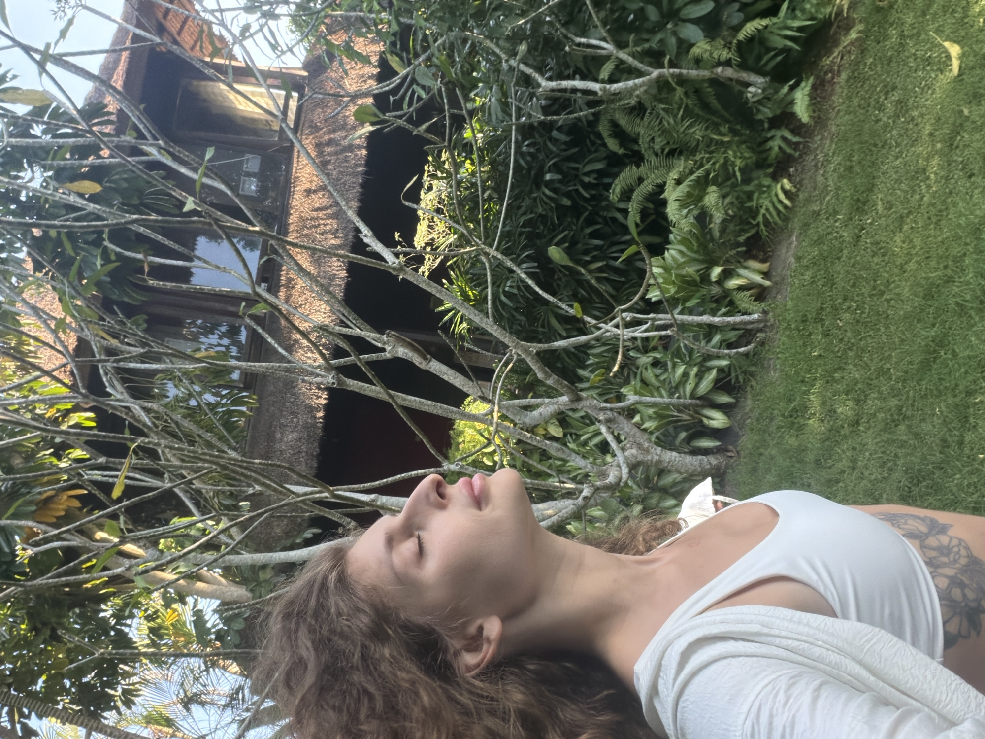 Woman photographs herself in tropical Indonesian garden setting