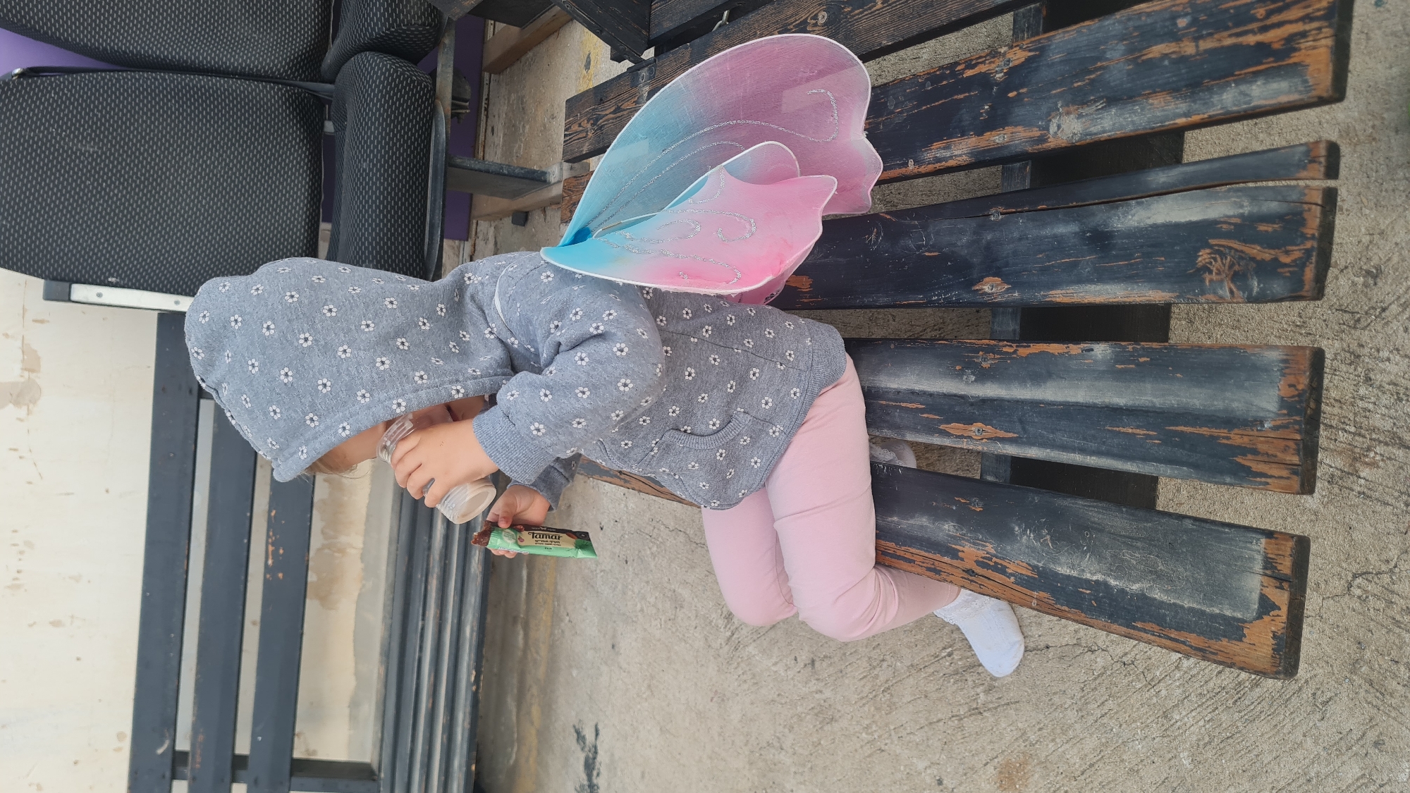 Child in fairy wings rests on bench in Rishon LeZion