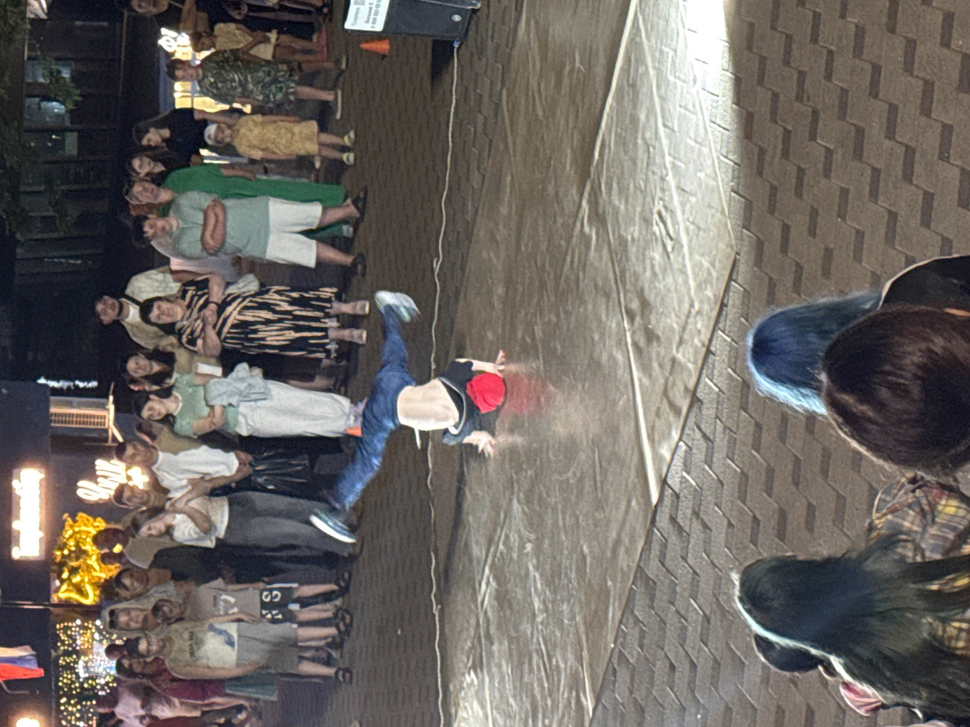 Breakdancers and street musicians perform for a nighttime plaza crowd