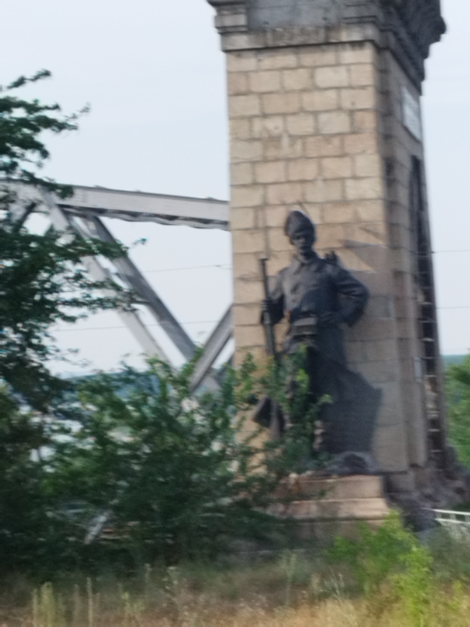 Danube crossing at Cernavodă: truss bridge, barges, and soldier statue