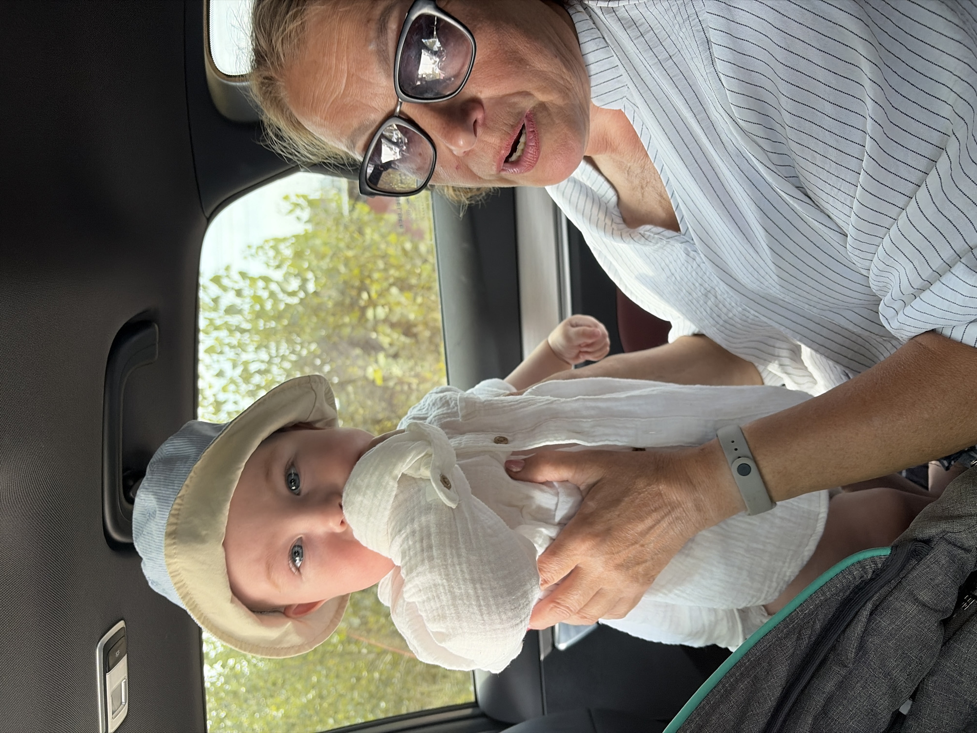 Baby in a hat held close inside a vehicle in Russia