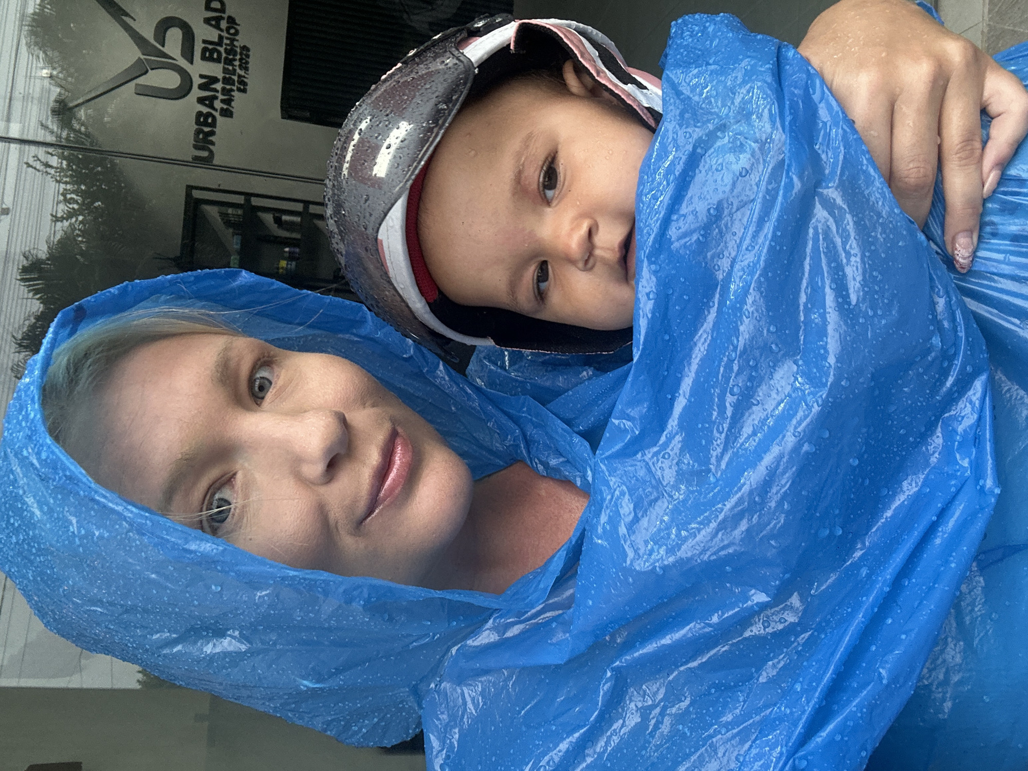 Woman and child shelter under poncho in North Kuta