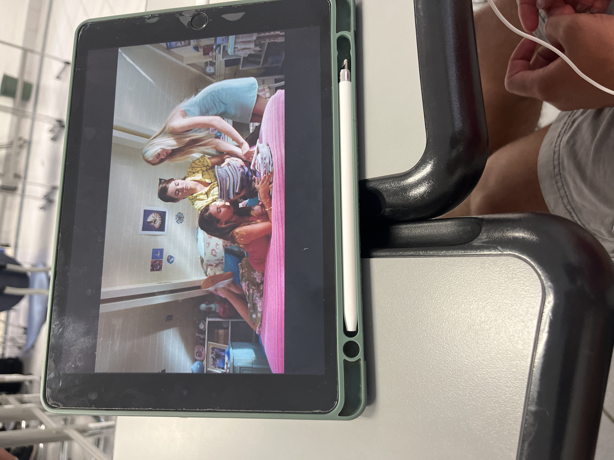 Tablet displays bedroom scene with three women, witness observes