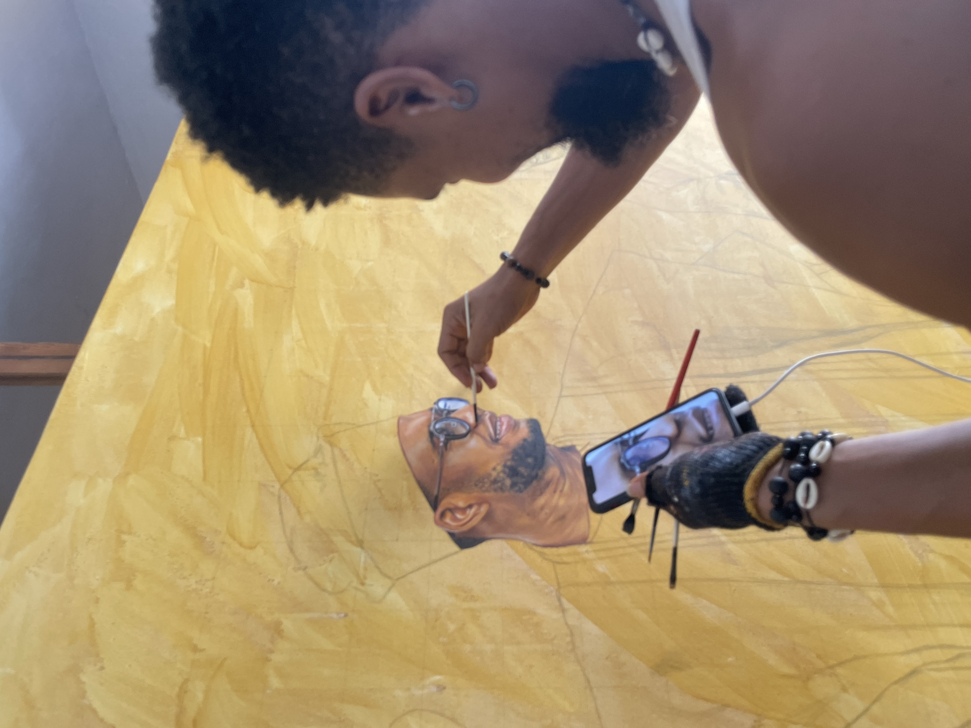 Artist paints bearded portrait on yellow canvas in Ado