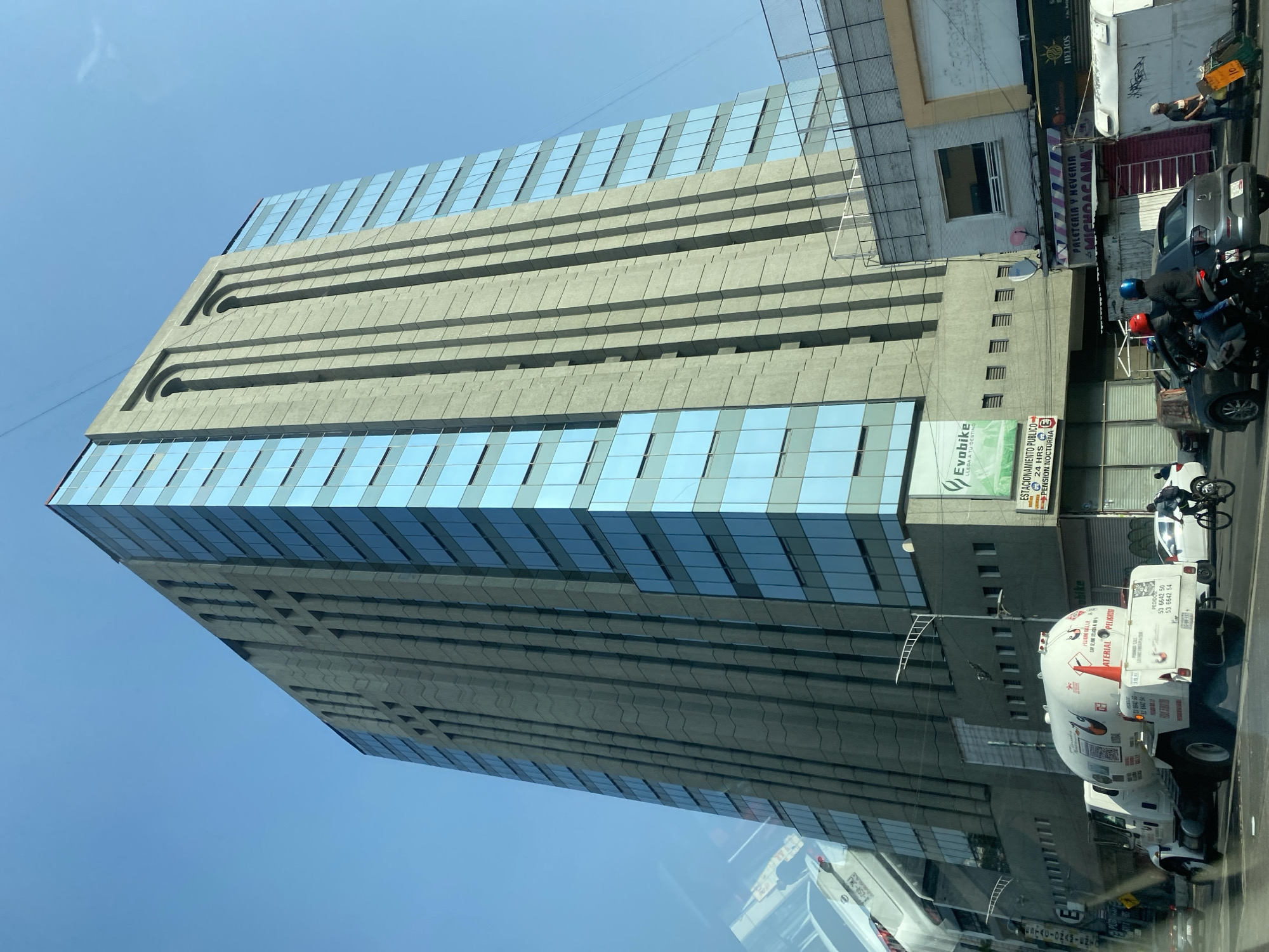 Tall glass-concrete building documented under clear skies