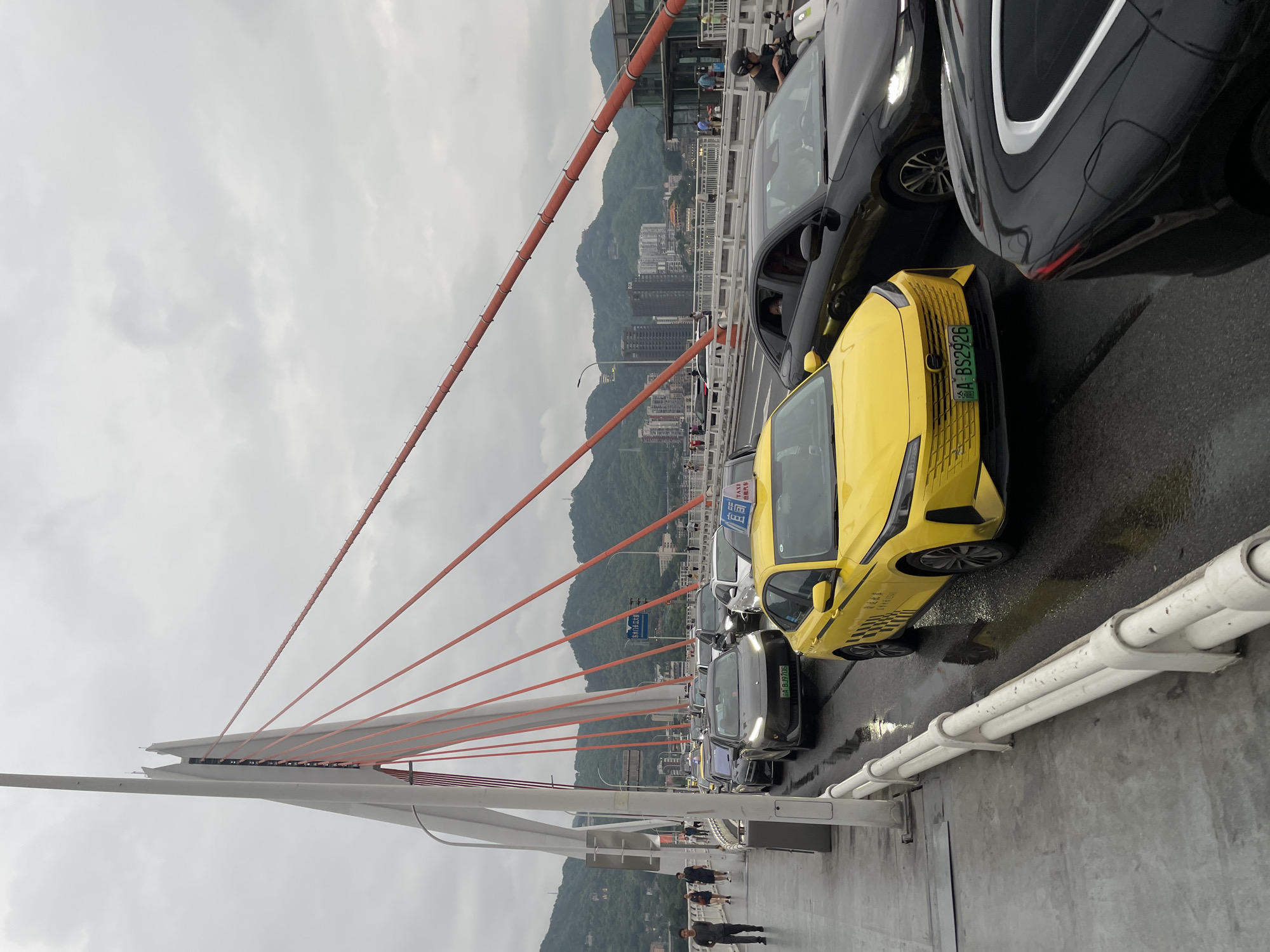 Slow traffic across a Chongqing suspension bridge on a rainy morning