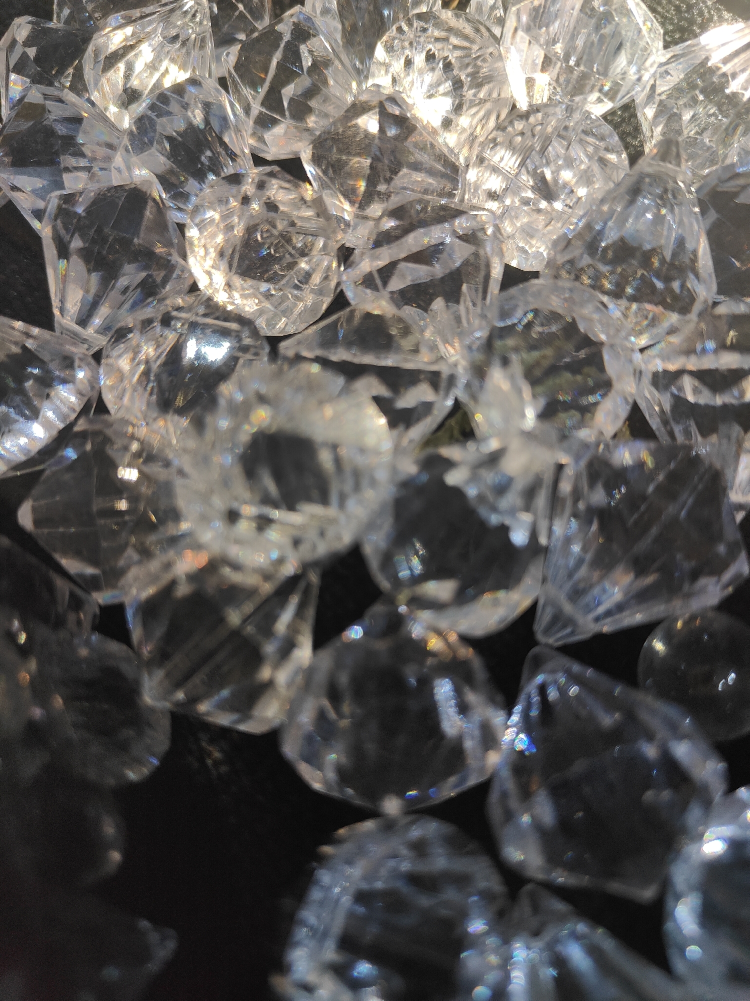 Clear faceted gemstones catch light on a dark surface