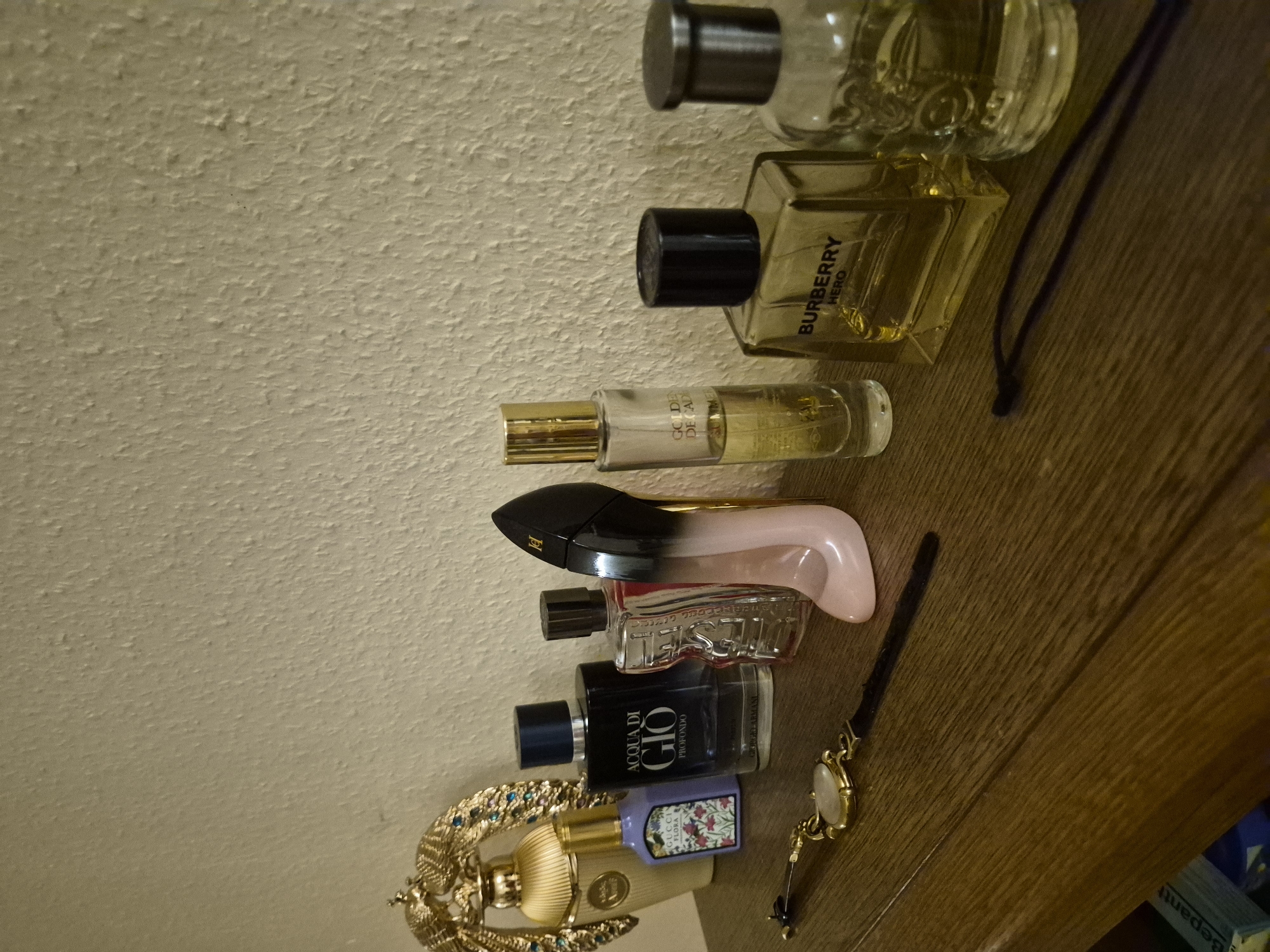 Perfume collection and accessories laid out on a wooden dresser