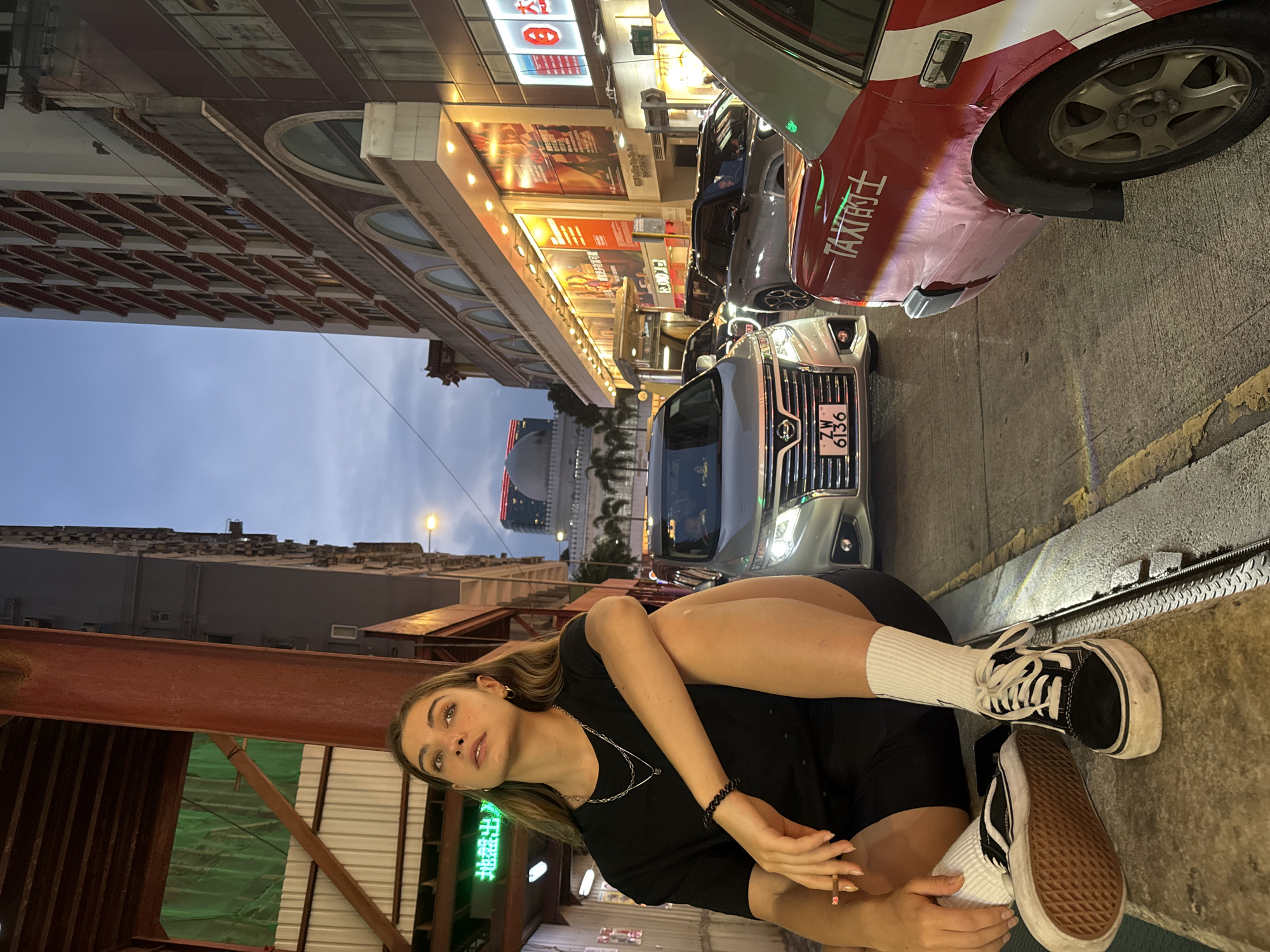 Woman sits on street ledge in Hong Kong nighttime scene