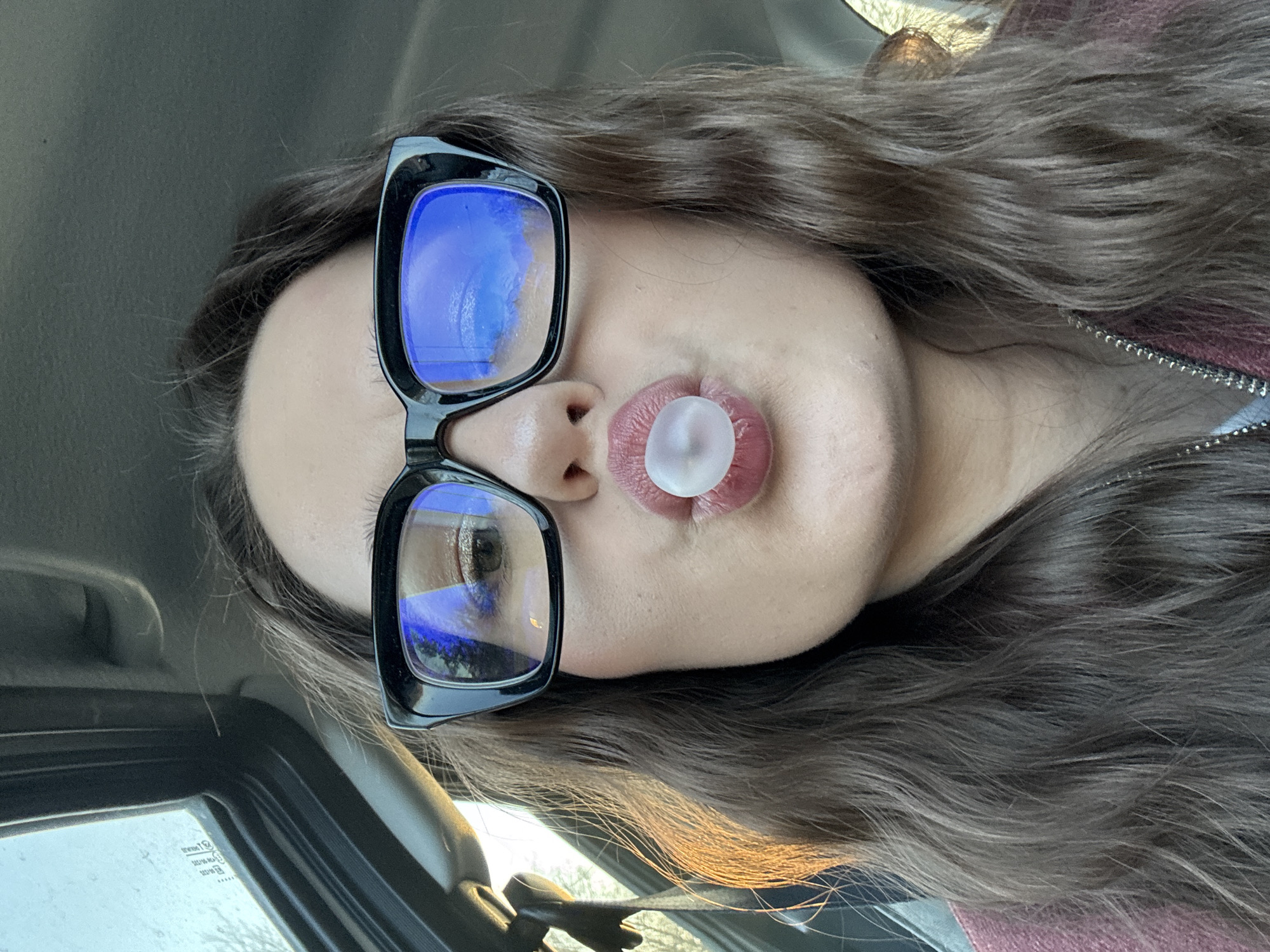 Woman blows bubble gum in car in Garevaya