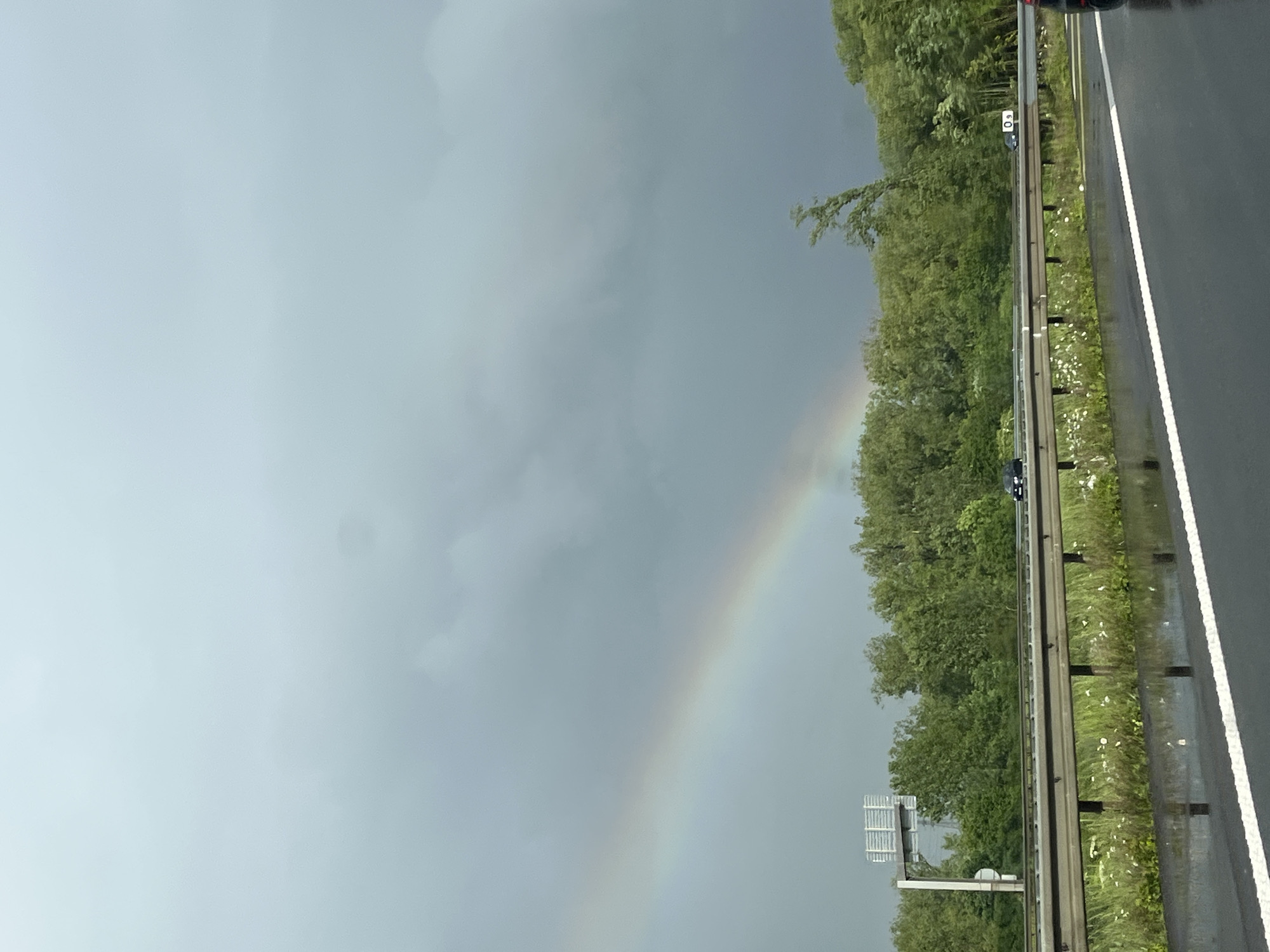 Rainbow appears over wet highway near Richemont, France