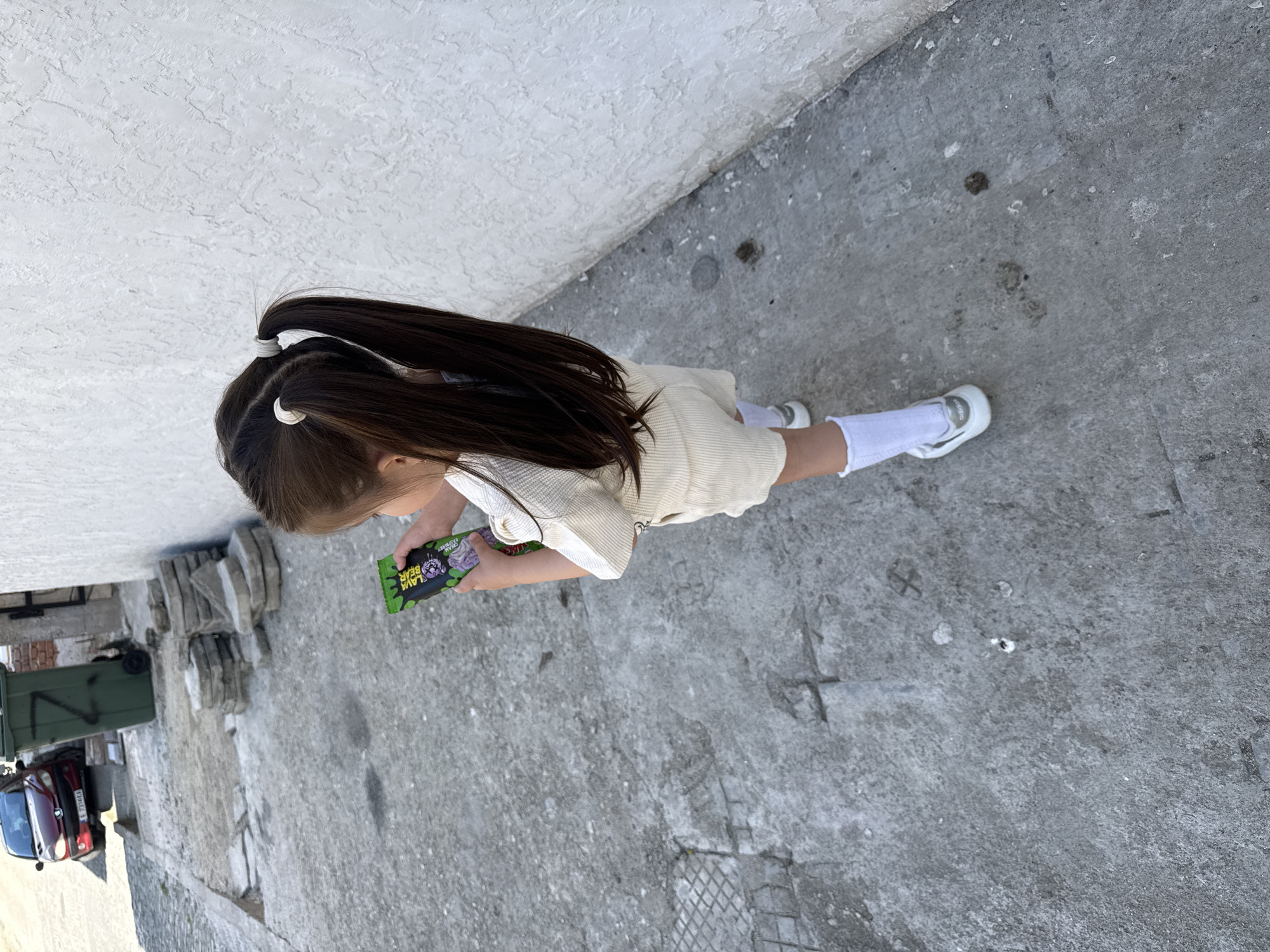 Girl in pigtails stands on sidewalk in Sandanski