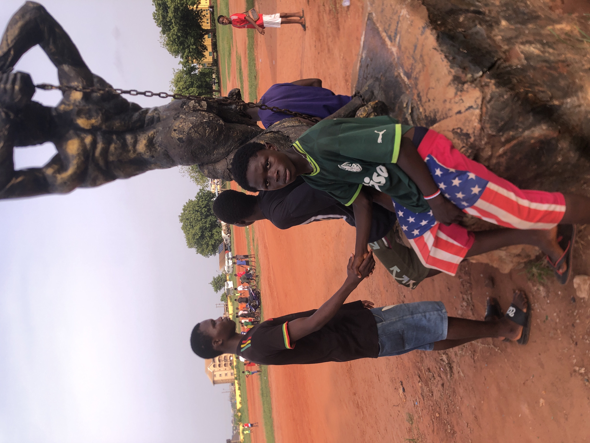 Young men play football near statue in Ukwu-Abwa, Nigeria