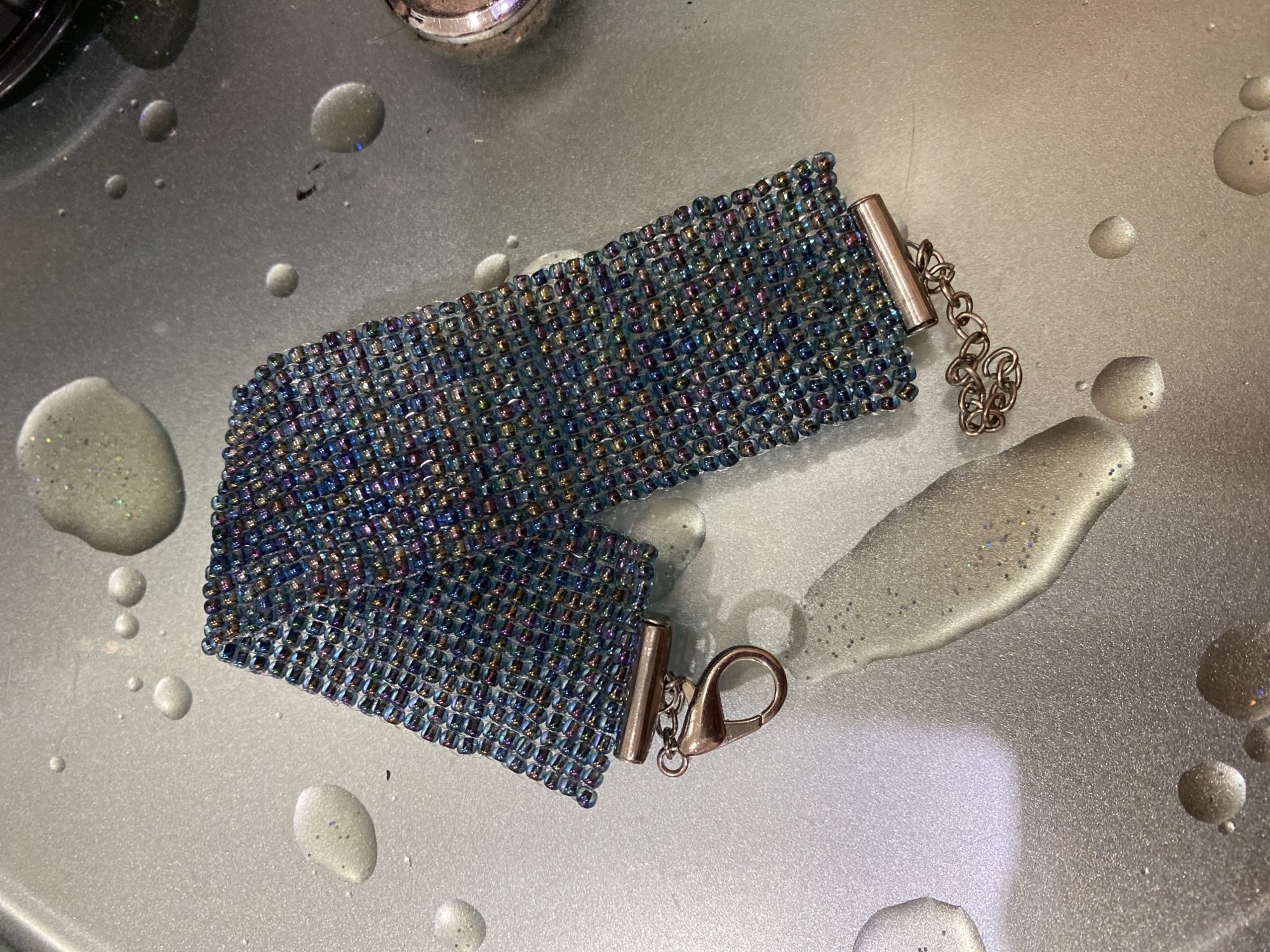 Two beaded bracelets, different styles, on metallic surfaces